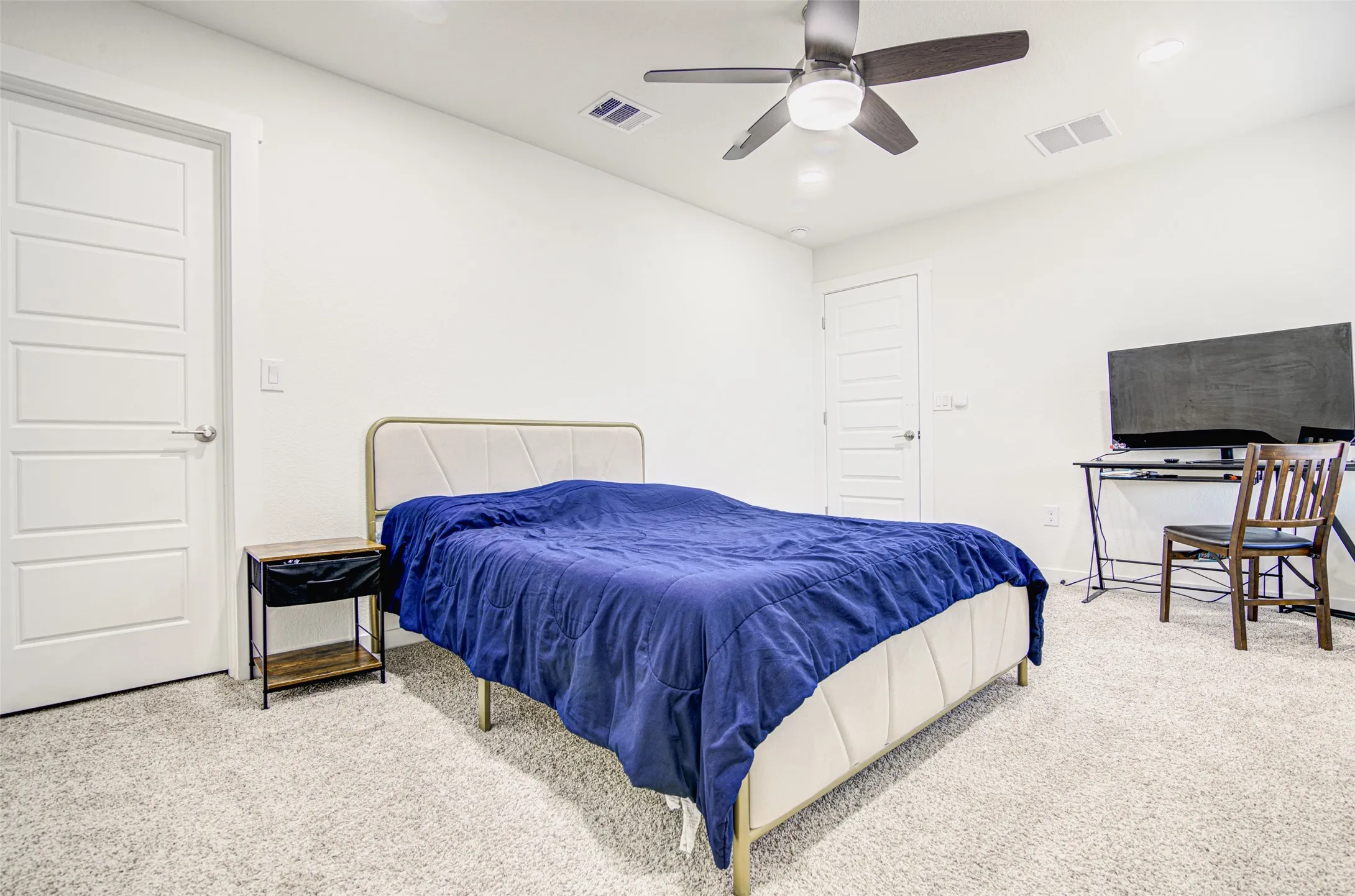 Plush carpet flooring, white walls, and a ceiling fan with integrated lighting