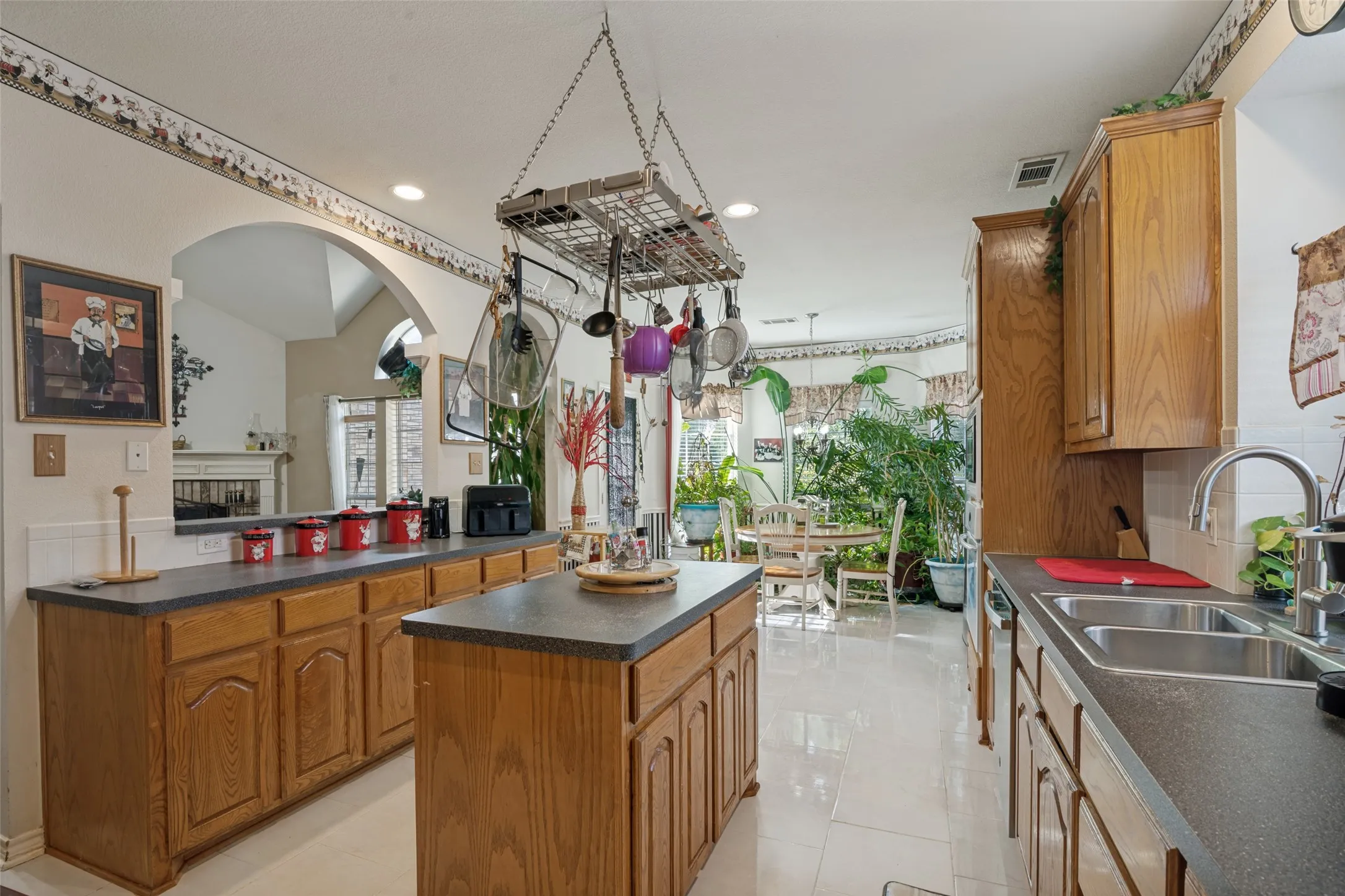 Kitchen featuring wood cabinetry, a center island, dual basin sink, and tile flooring