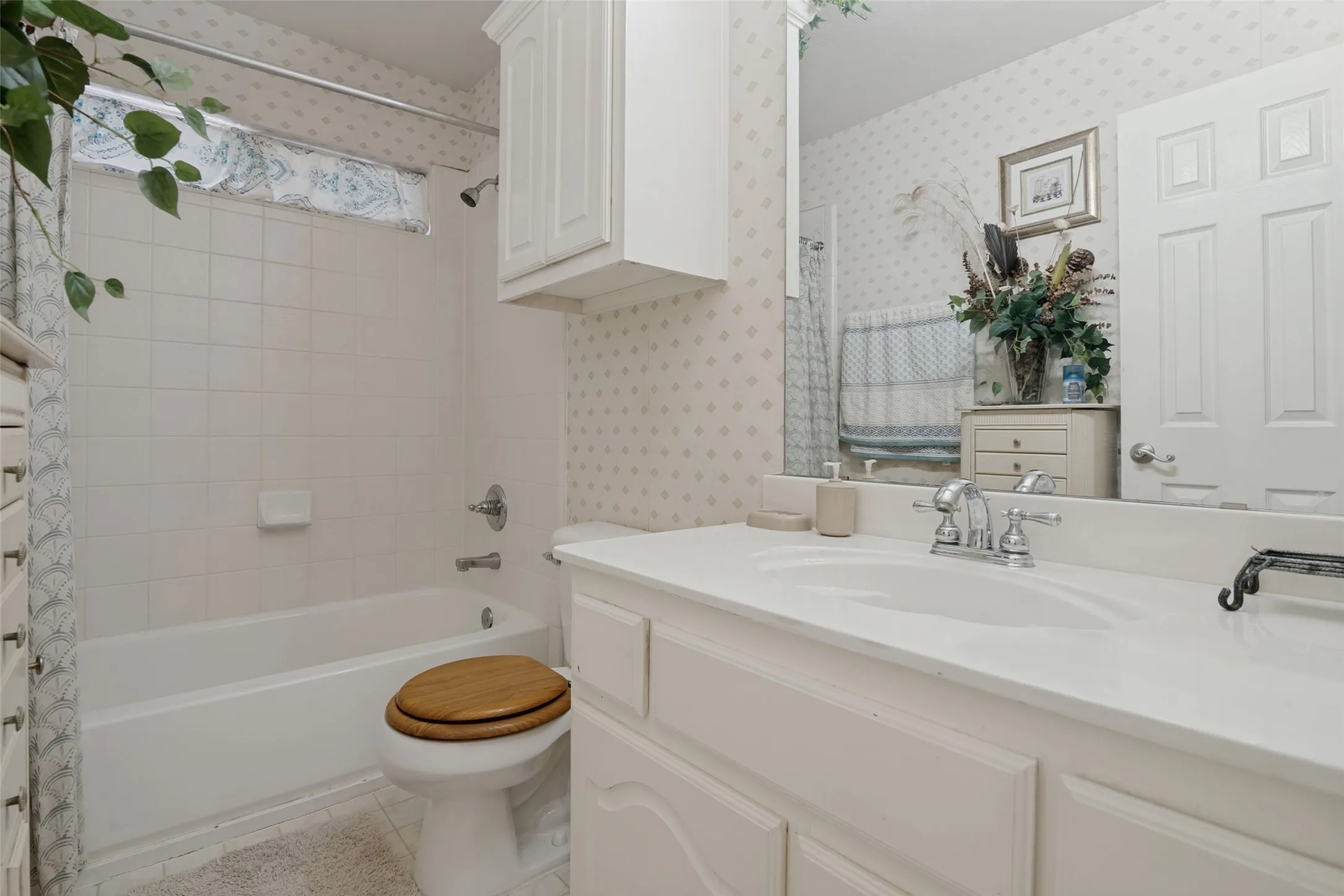 Vanity with integrated sink, white cabinetry, and wall-mounted mirror
