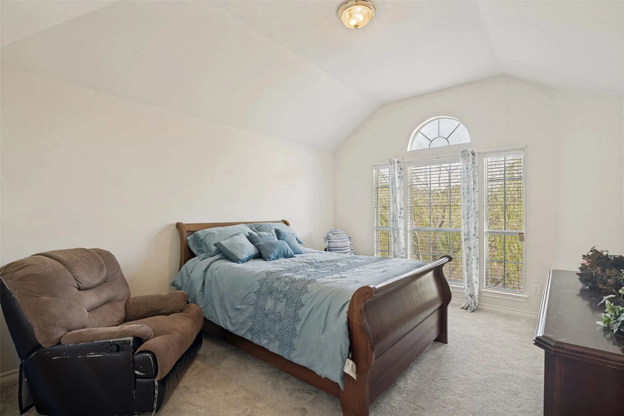Vaulted ceiling with an arched transom window, two vertical windows with blinds, and flush-mount ceiling lighting