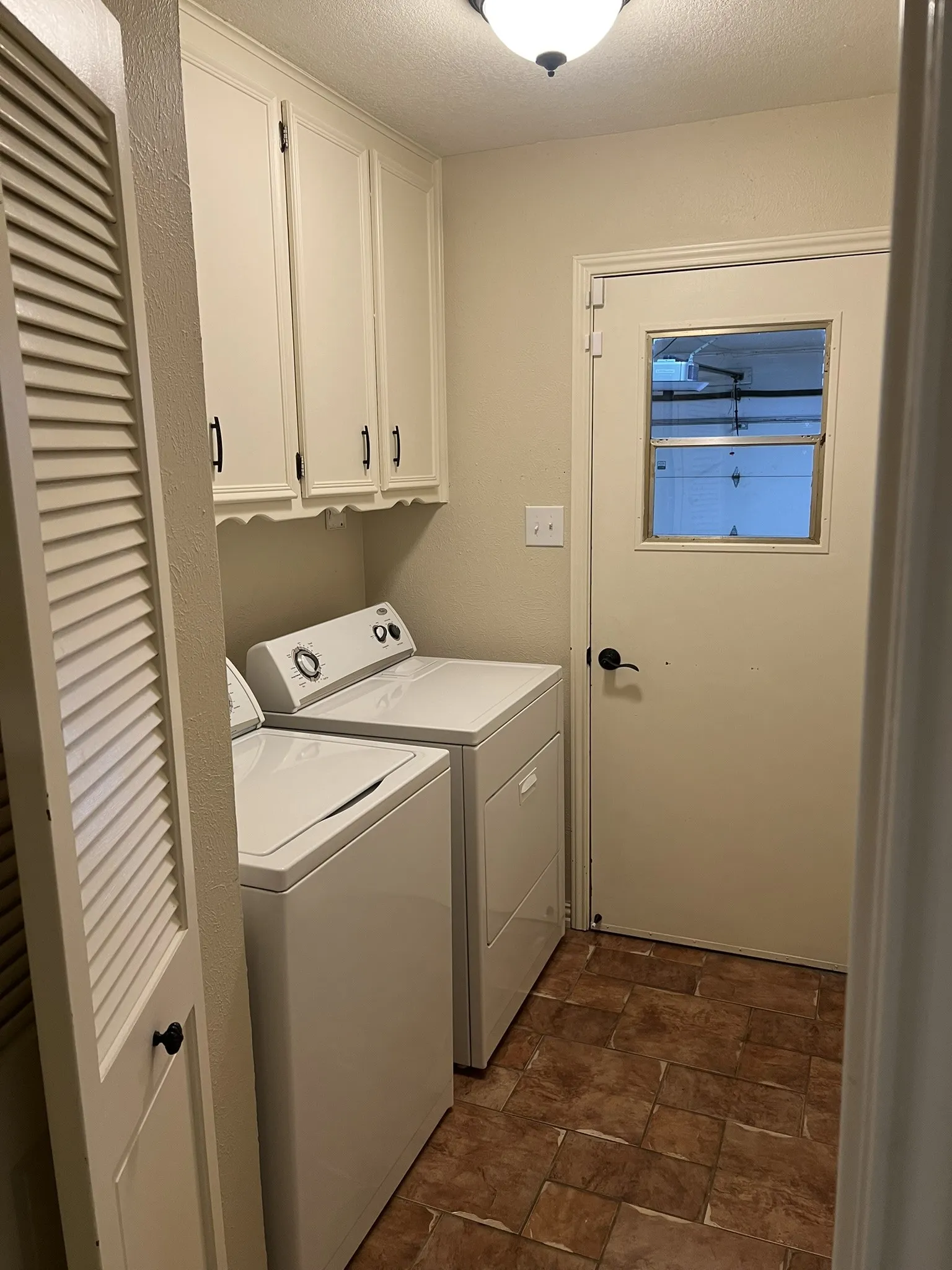 Laundry Room Overhead cabinetry, tile-finish flooring, and a louvered door