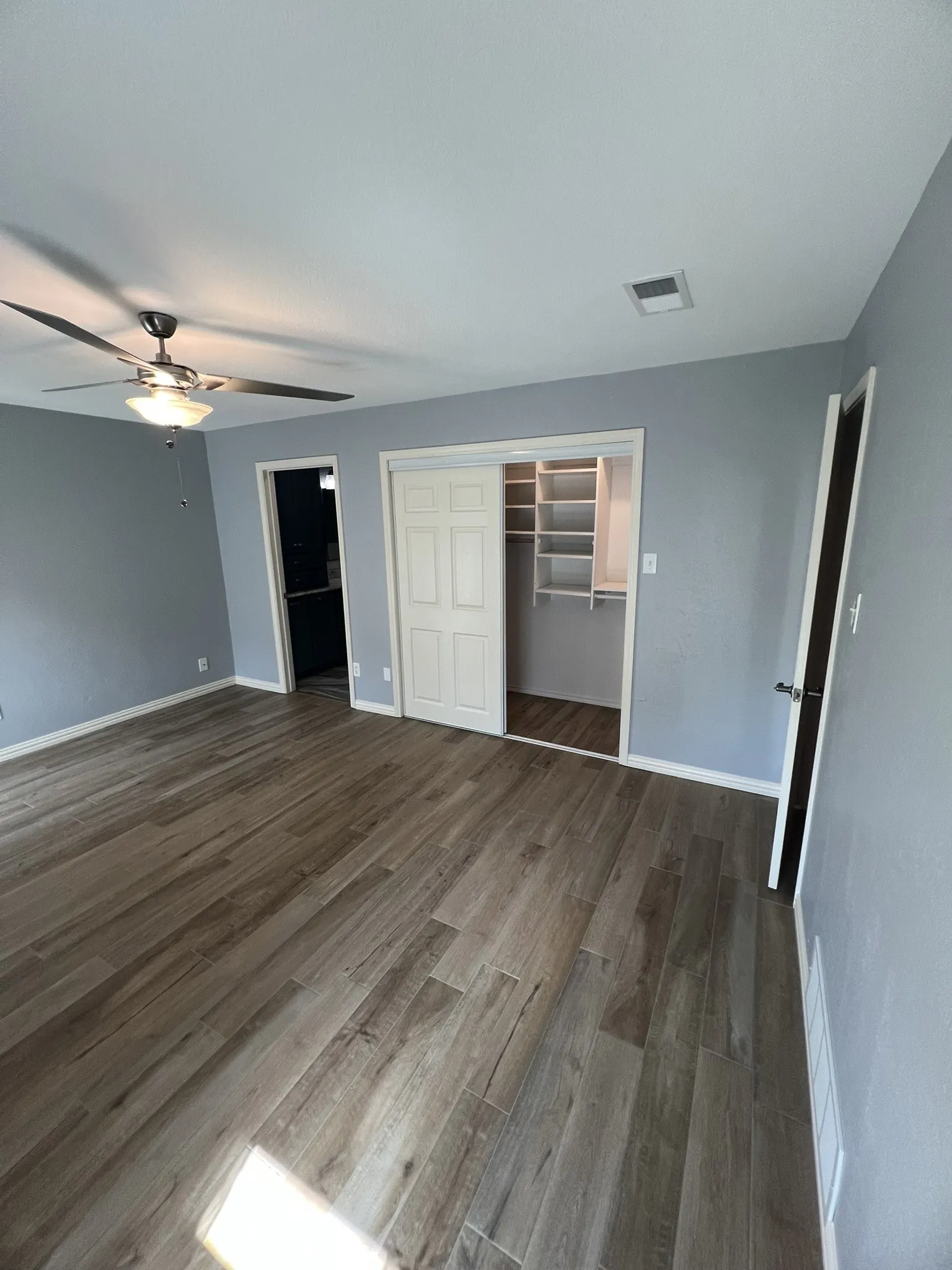 Master Bedroom Wood-finish flooring, ceiling fan, and sliding closet doors with built-in shelving