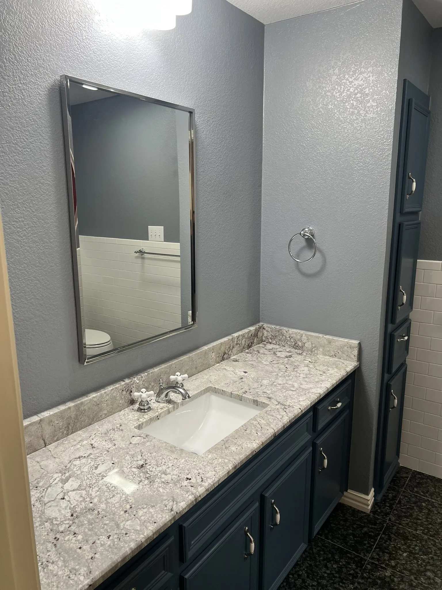 Full Bath - Vanity featuring a stone countertop, an undermount sink, and dark blue cabinetry with silver-tone hardware
