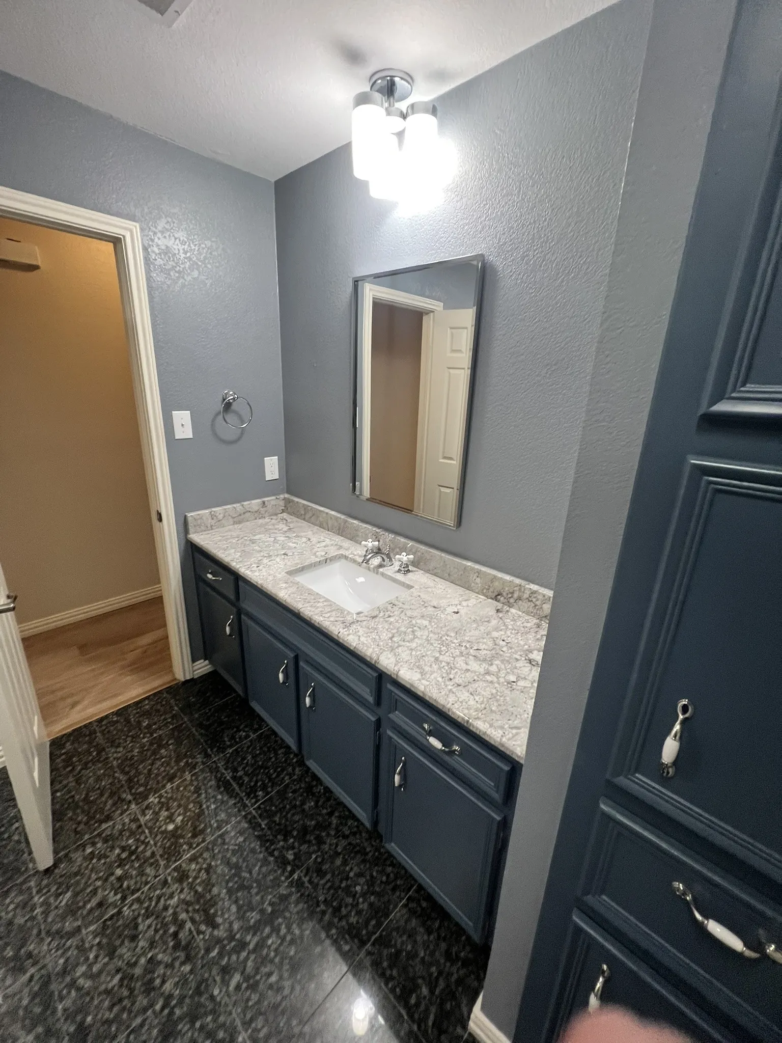 Full Bath - Built-in vanity with a single basin sink, light-toned countertop, and dark cabinetry