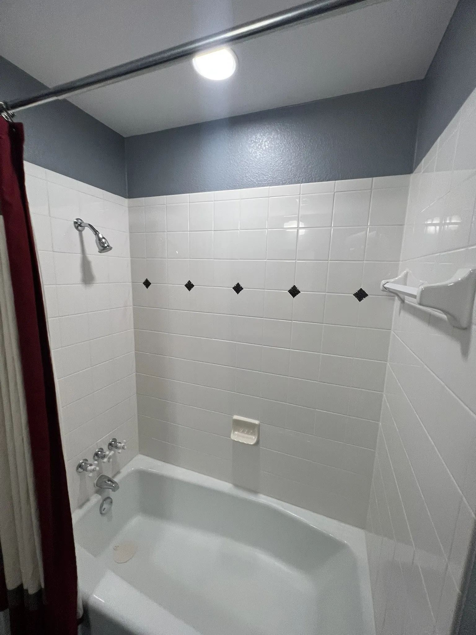 Full Bath - Bathtub with a shower fixture, white subway tile surround with diamond accents, and a fixed shower rod