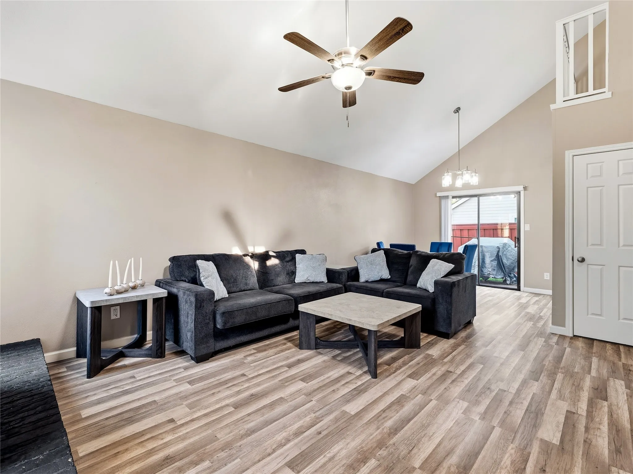 Vaulted ceiling with a ceiling fan, wood-finish flooring, sliding glass door, and a built-in window