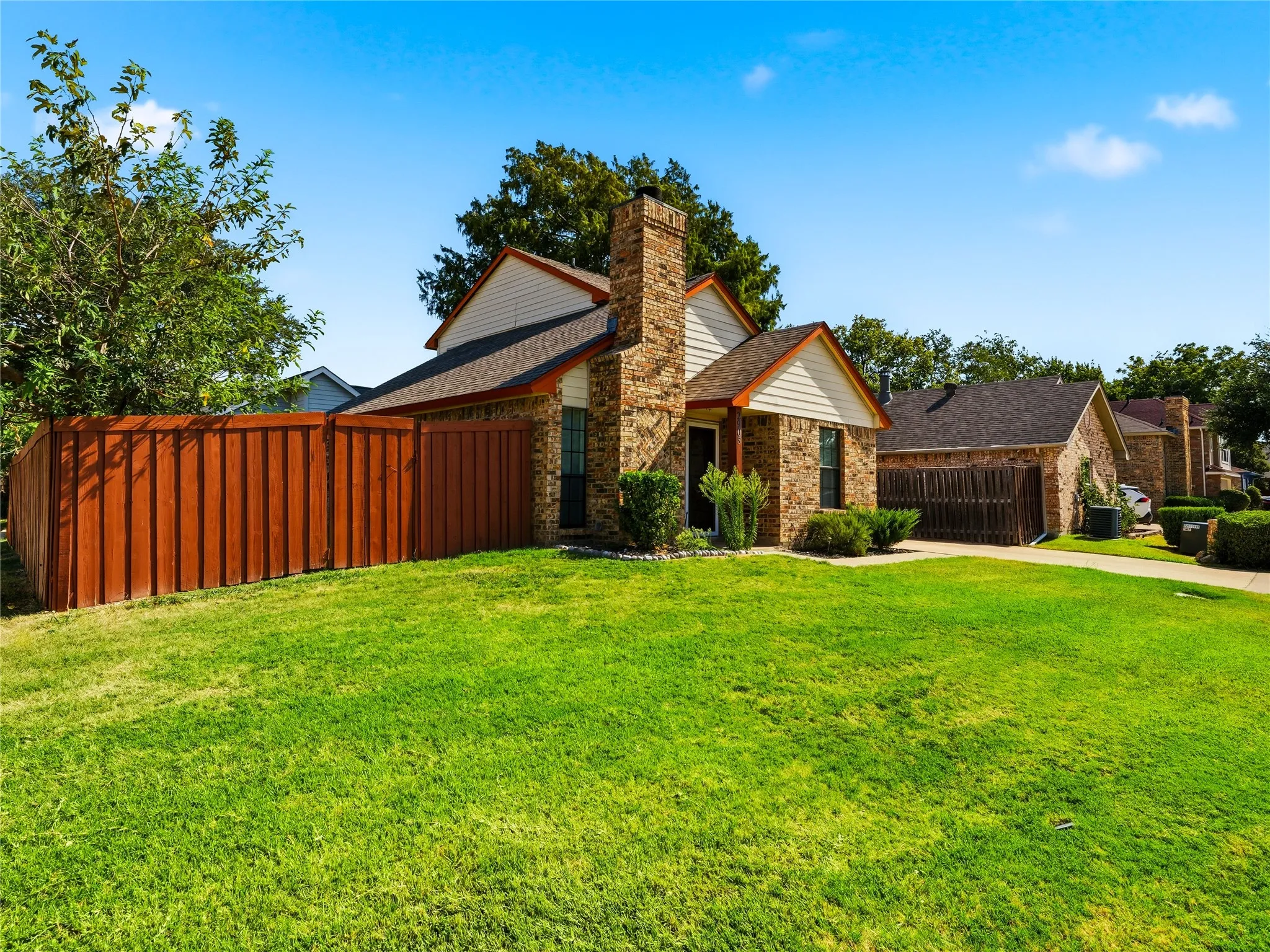 Brick exterior with a prominent brick chimney, gabled roofline, and a private wooden fence