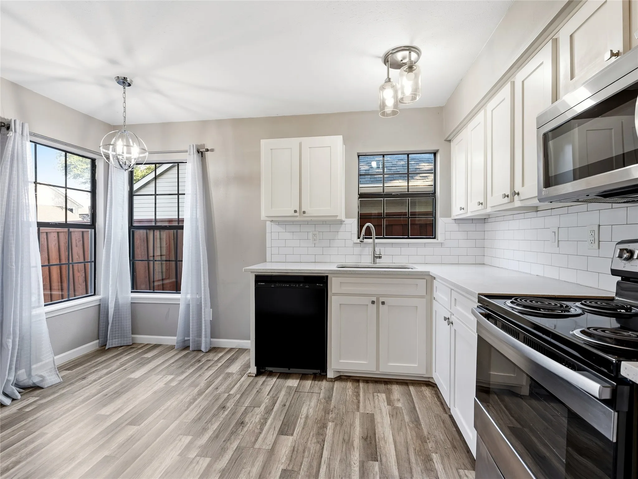 Kitchen featuring white cabinetry, subway tile backsplash, stainless steel appliances, and wood-finish flooring