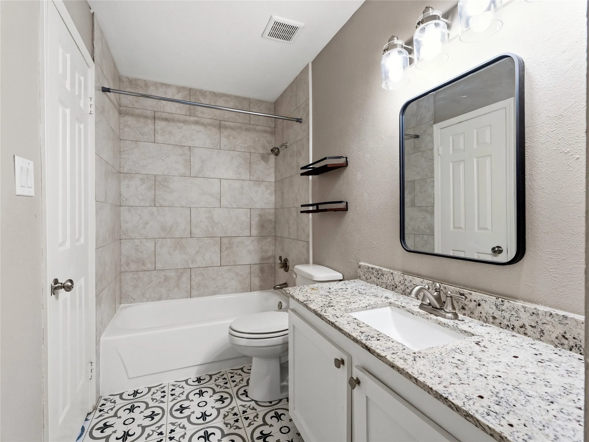 White vanity with a speckled countertop, undermount sink, and chrome faucet