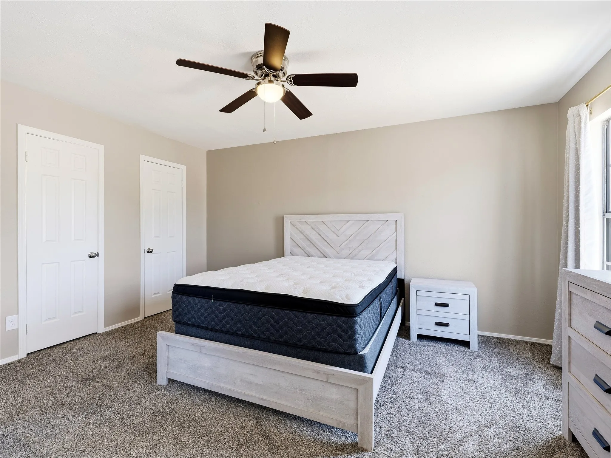 Recessed panel doors, ceiling fan with integrated lighting, window with curtain rod, and neutral wall tones