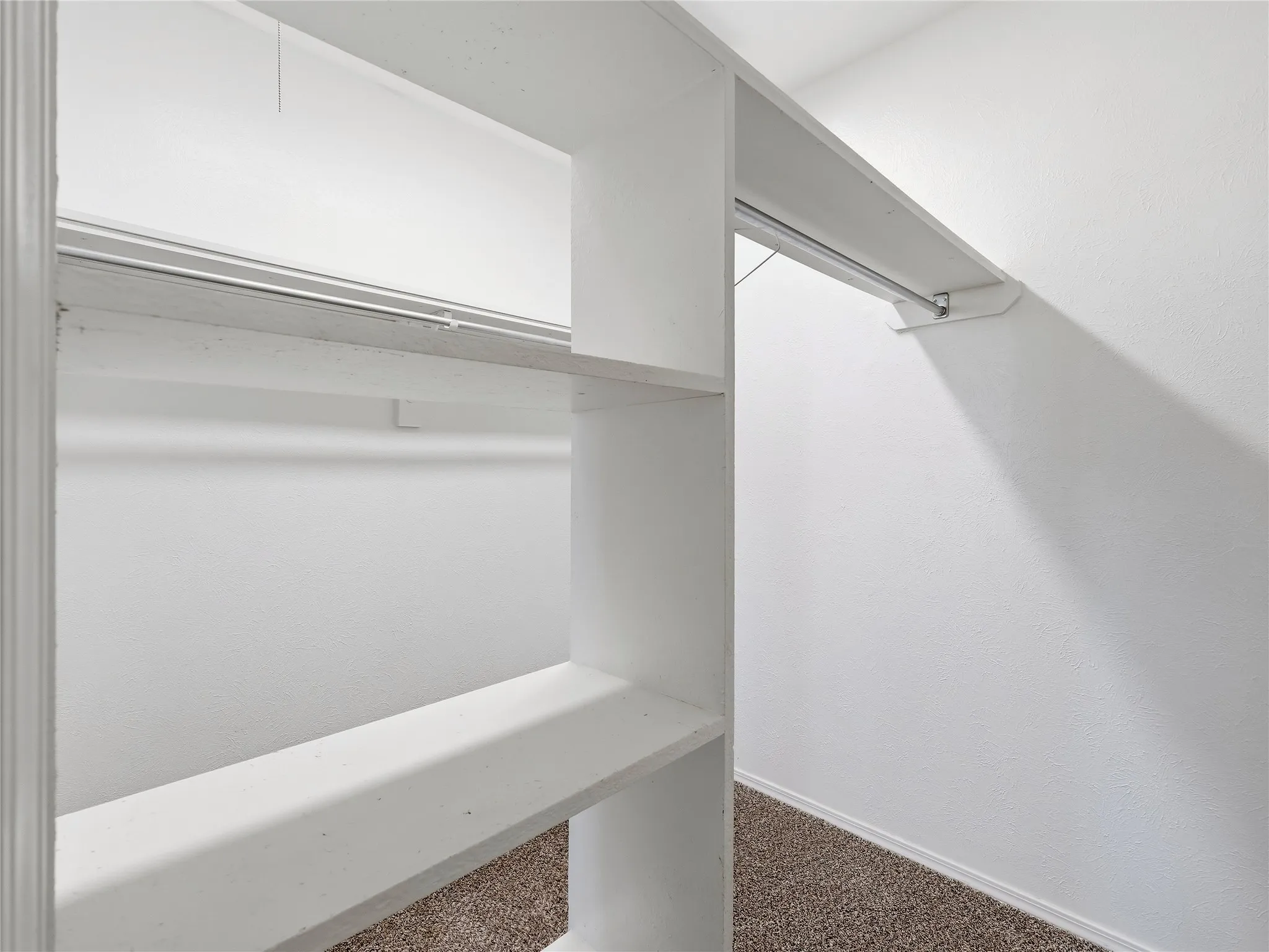 Built-in shelving with hanging rods and carpet flooring