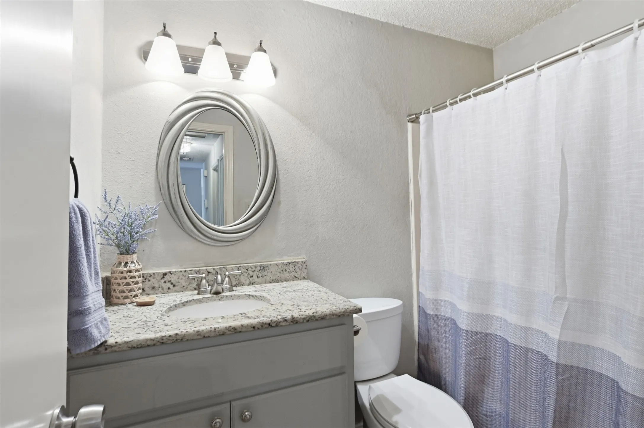 Vanity with granite-style countertop, undermount sink, gray cabinetry, and brushed nickel faucet