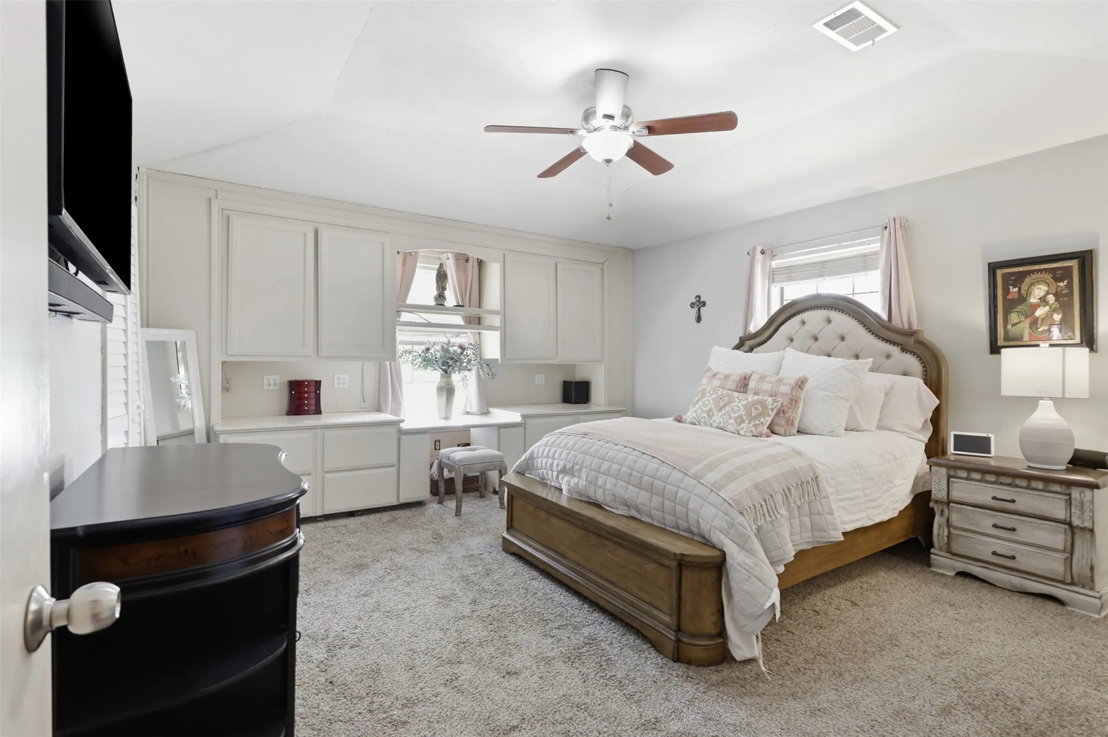Built-in cabinetry, window, ceiling fan, and carpeted flooring