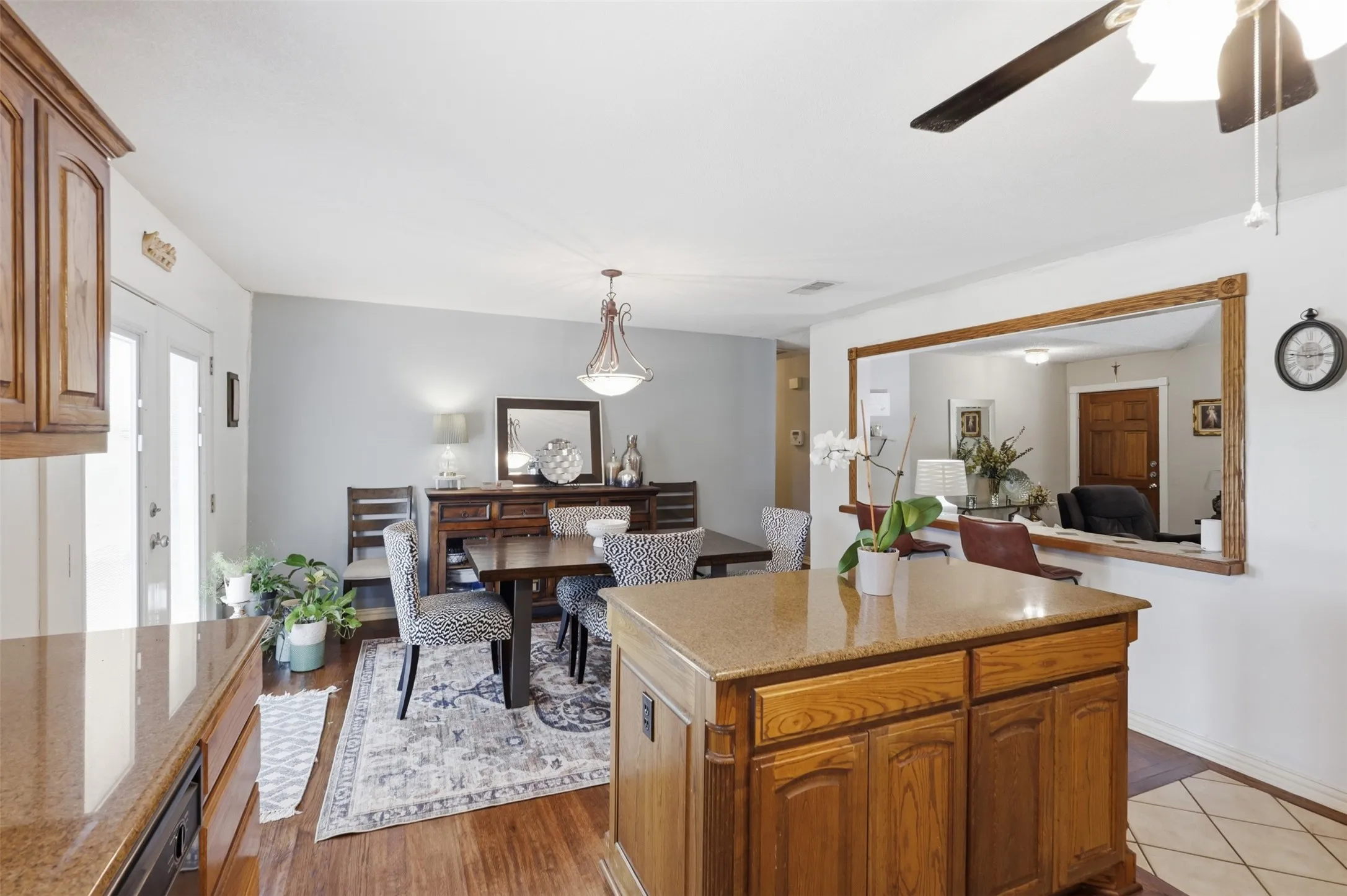 Kitchen island with granite-finish countertop, wood-finish cabinetry, and built-in ceiling fan