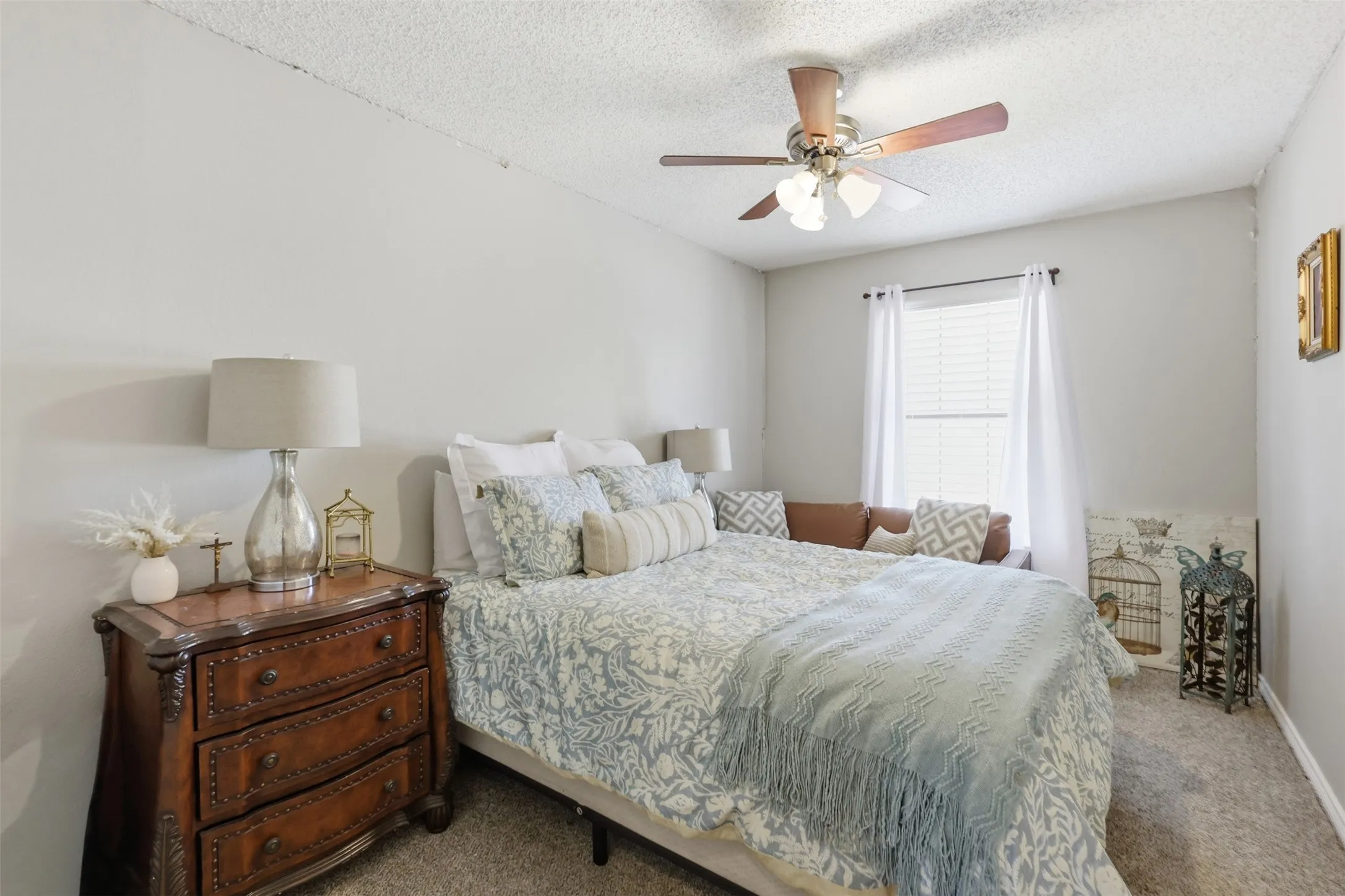 Recessed window alcove, ceiling fan with light fixture, neutral wall color, and textured carpet flooring