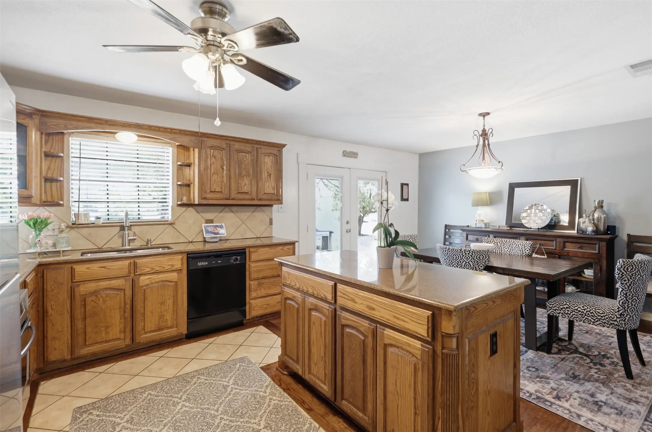 Kitchen with wood cabinetry, tile backsplash, and built-in dishwasher