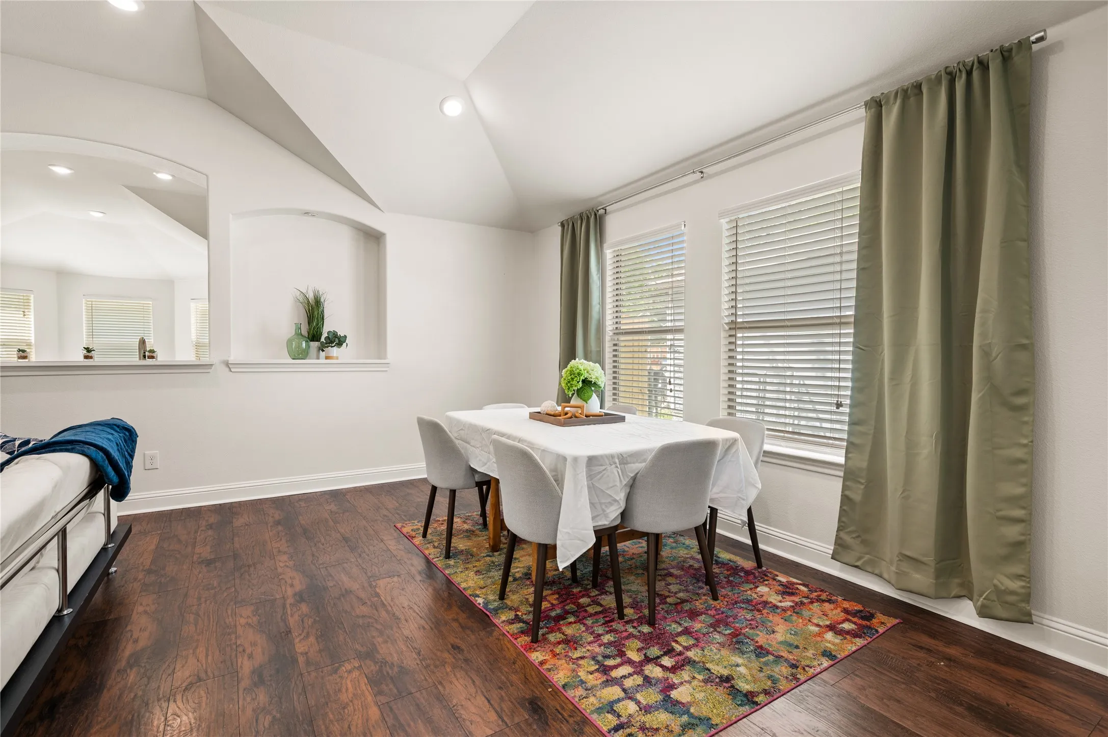 Vaulted ceiling, recessed lighting, wood-finish flooring, multiple windows with blinds, arched wall niches
