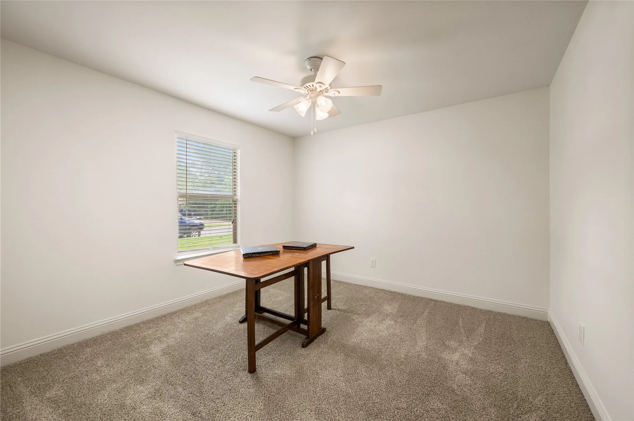 Carpeted room with a ceiling fan, window with blinds, and white walls