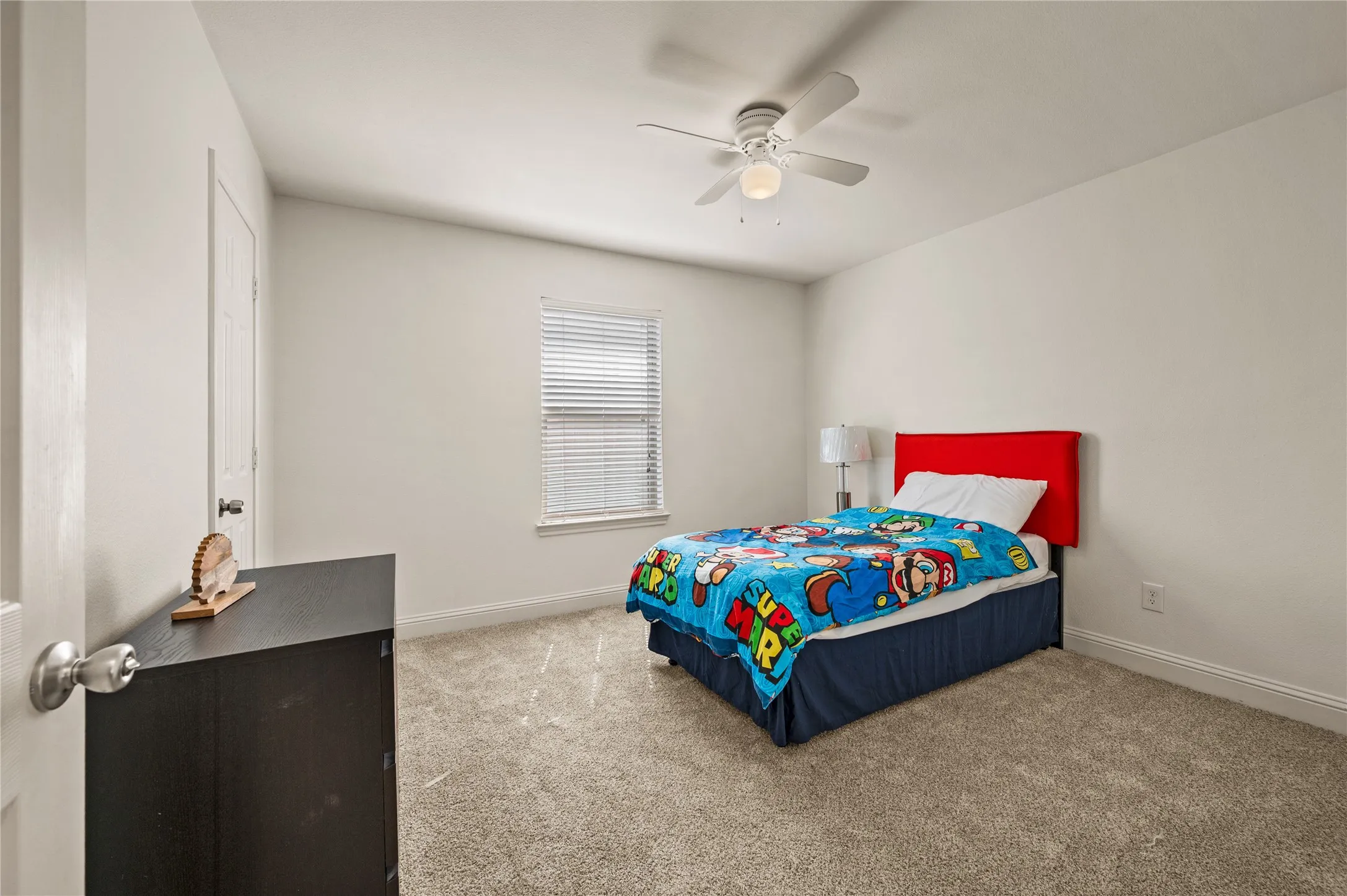 Room featuring neutral wall tones, textured carpeting, window with blinds, and a ceiling fan with integrated lighting