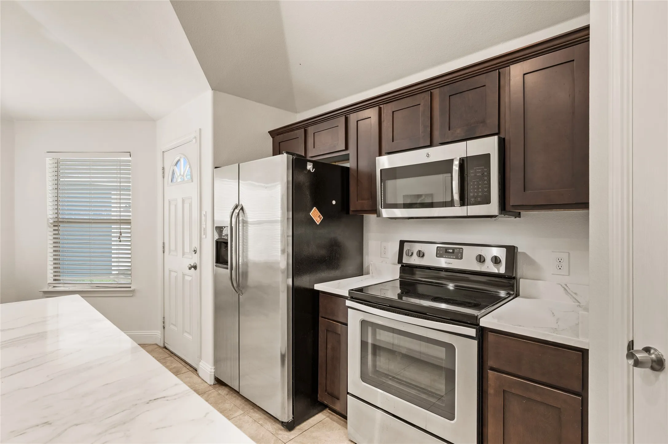 Kitchen featuring dark wood-finish cabinetry, stainless steel appliances, and light-toned countertops