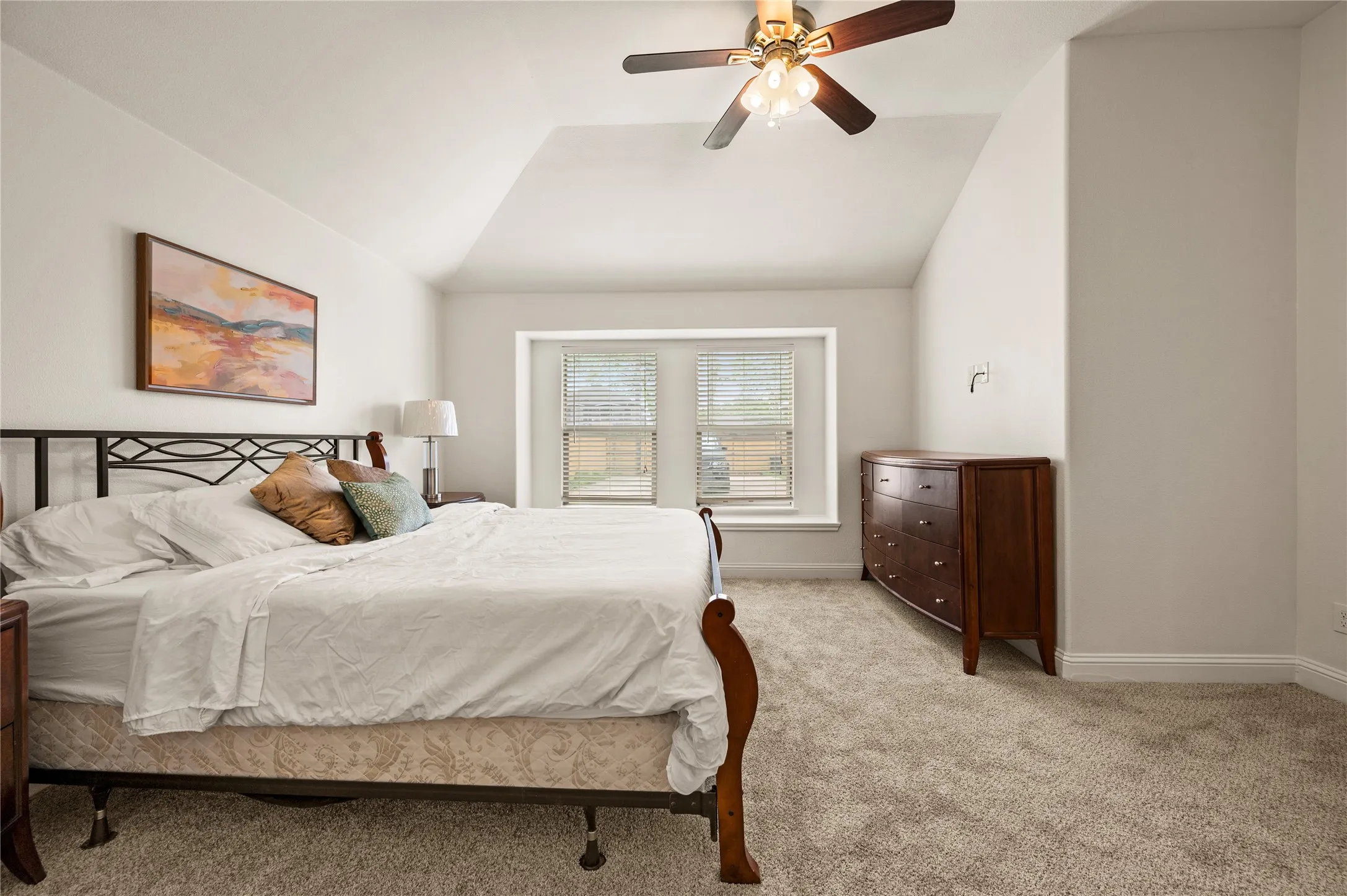 Carpeted room with vaulted ceiling and a ceiling fan