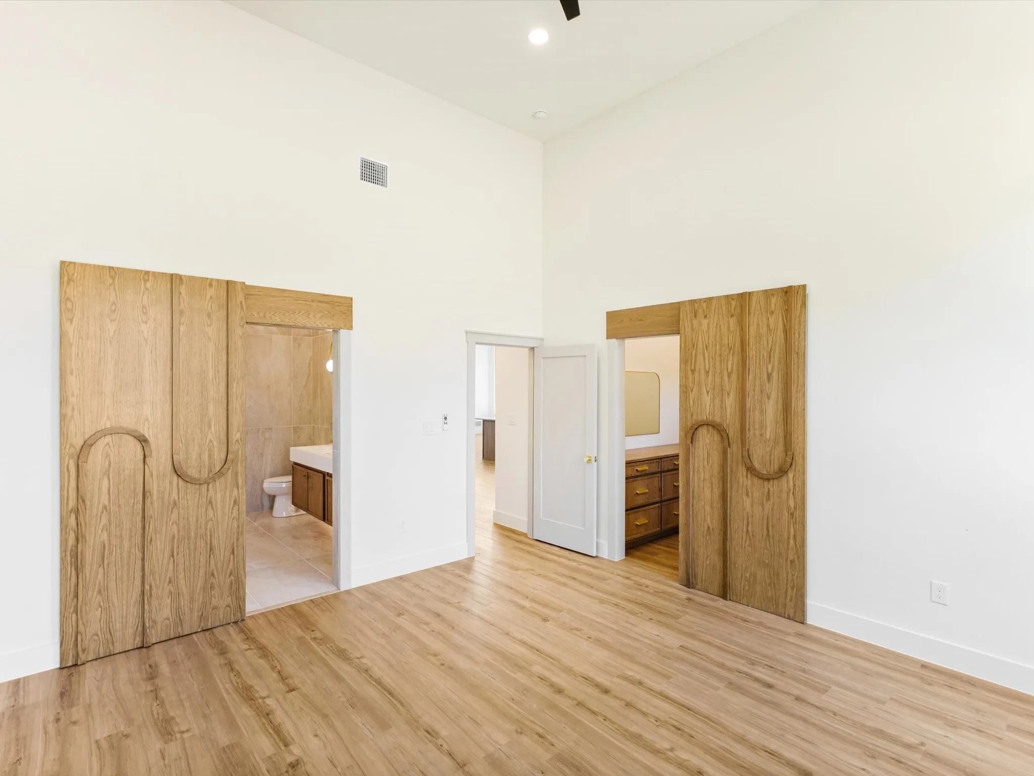 Vaulted ceiling with a recessed light fixture, wood-finish flooring, and white wall finishes