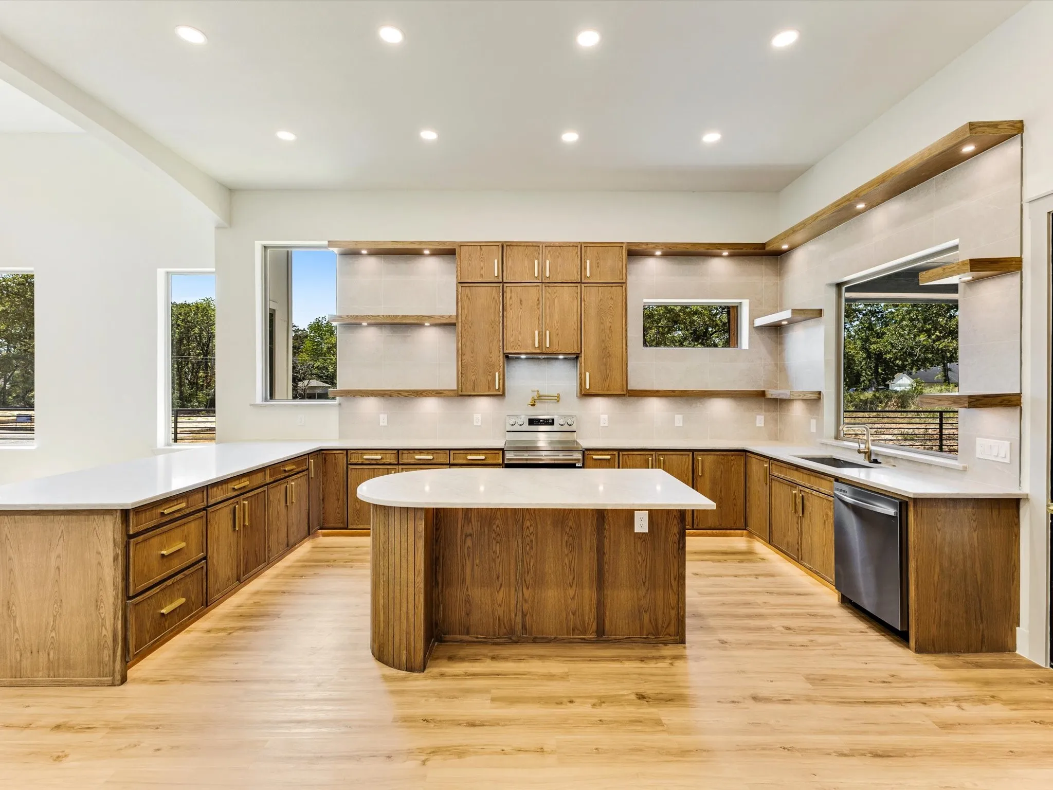 Kitchen featuring wood-finish cabinetry, light countertops, wood-finish flooring, recessed lighting, and stainless steel appliances