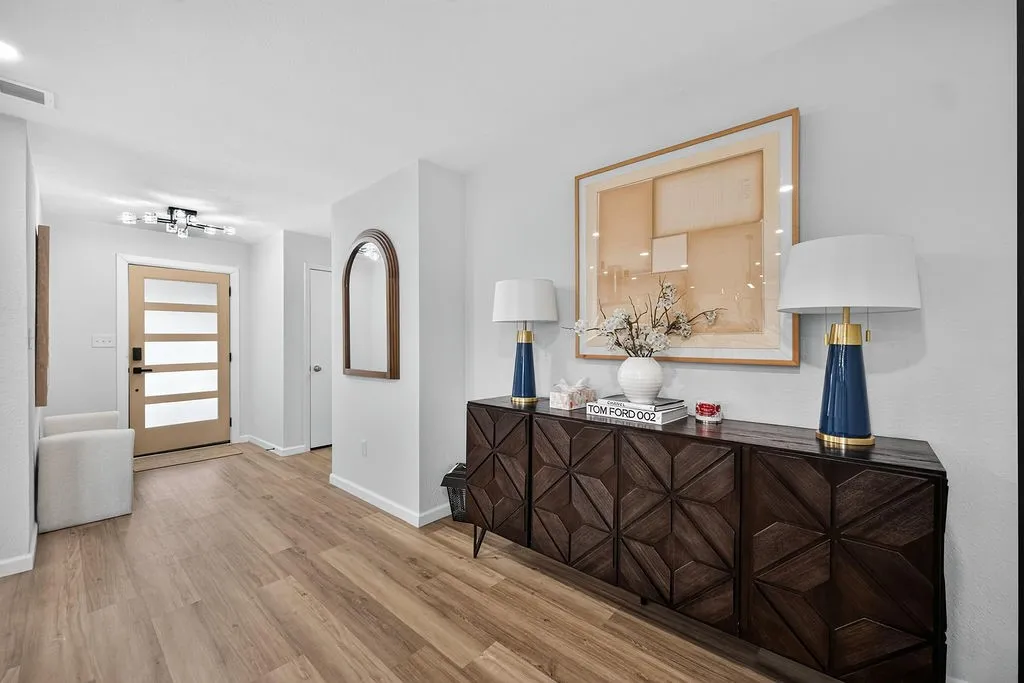 Entryway featuring wood-finish flooring, a modern front door with frosted glass panels, and a contemporary ceiling light fixture