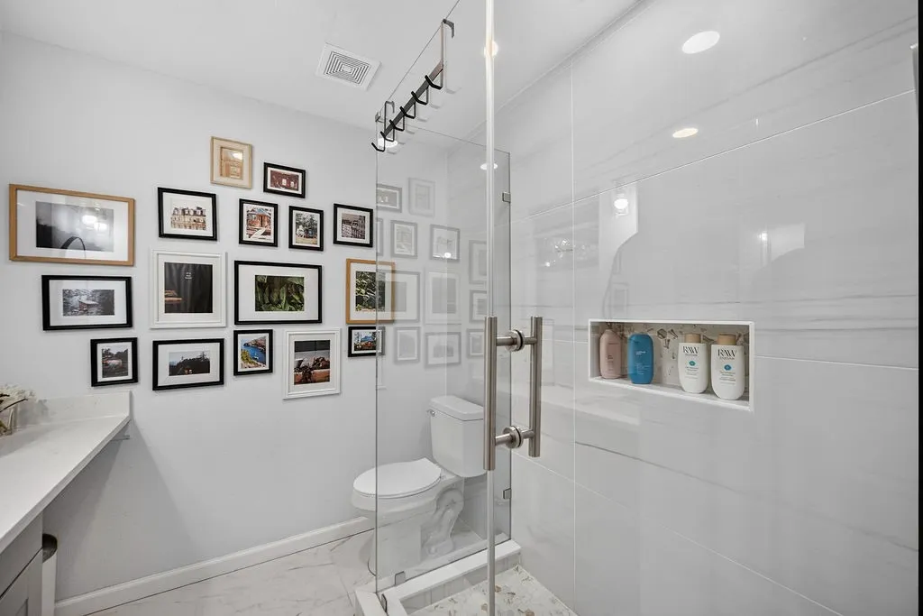 Spa-inspired primary bathroom featuring a frameless glass-enclosed shower with subway tile surround, white subway tile accent wall, recessed shelving niche, polished chrome fixtures, and recessed ceiling lighting