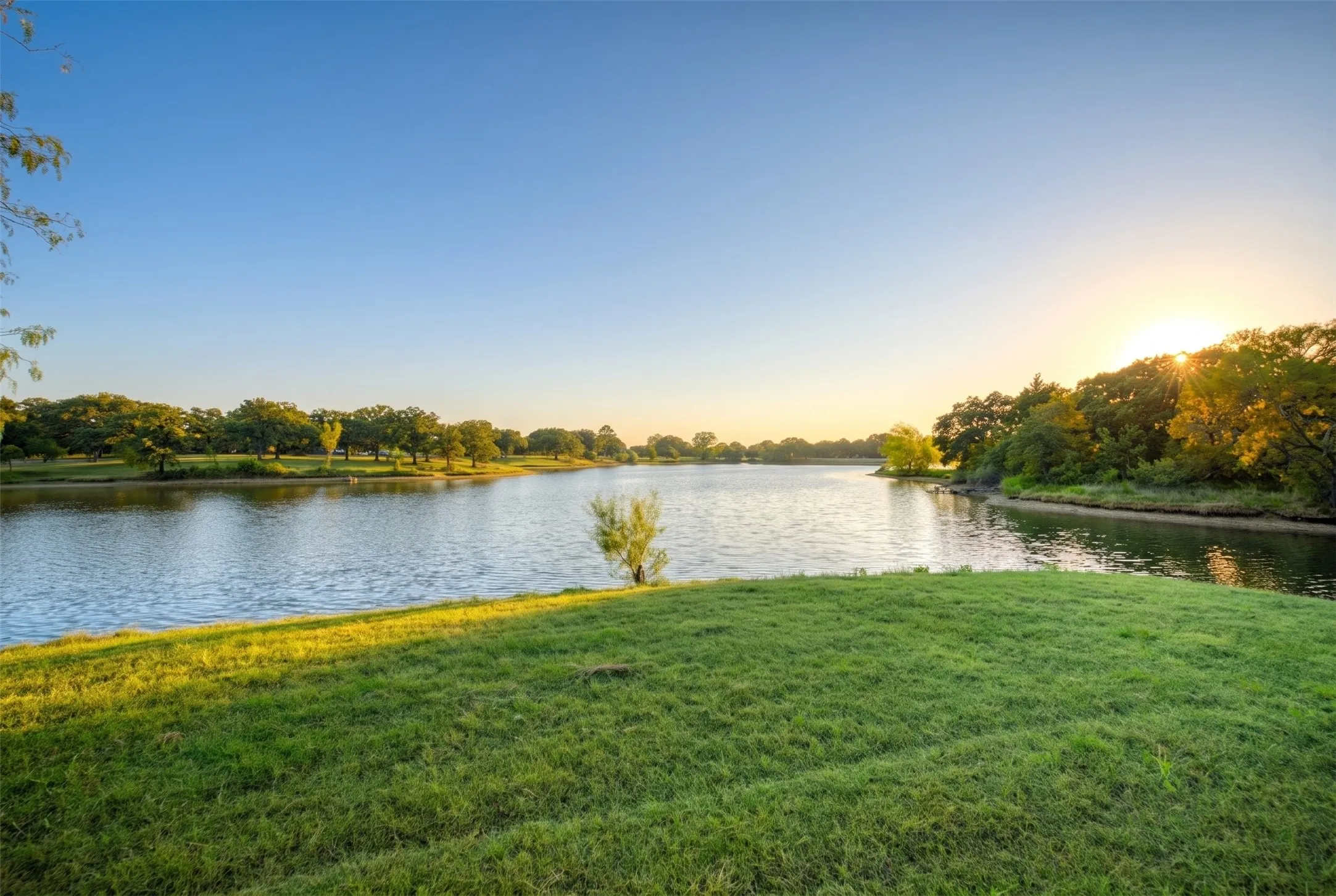 Expansive water feature with natural shoreline and lush green spaces