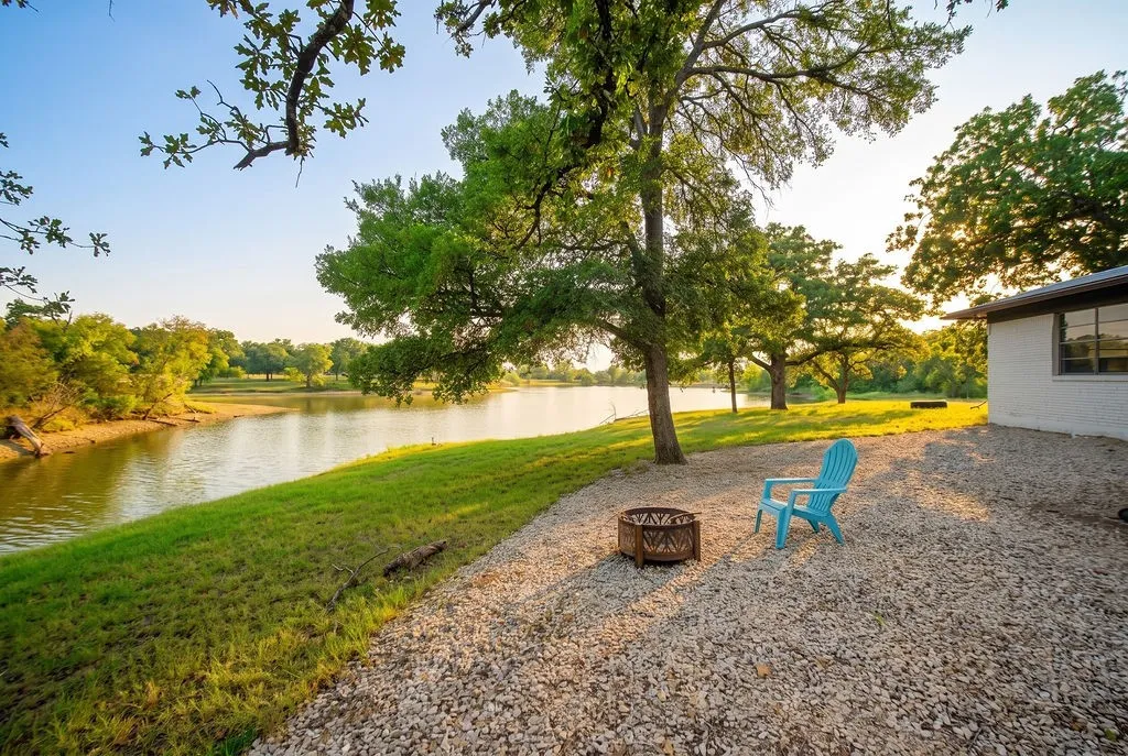 Waterfront setting with a gravel patio and a fire pit