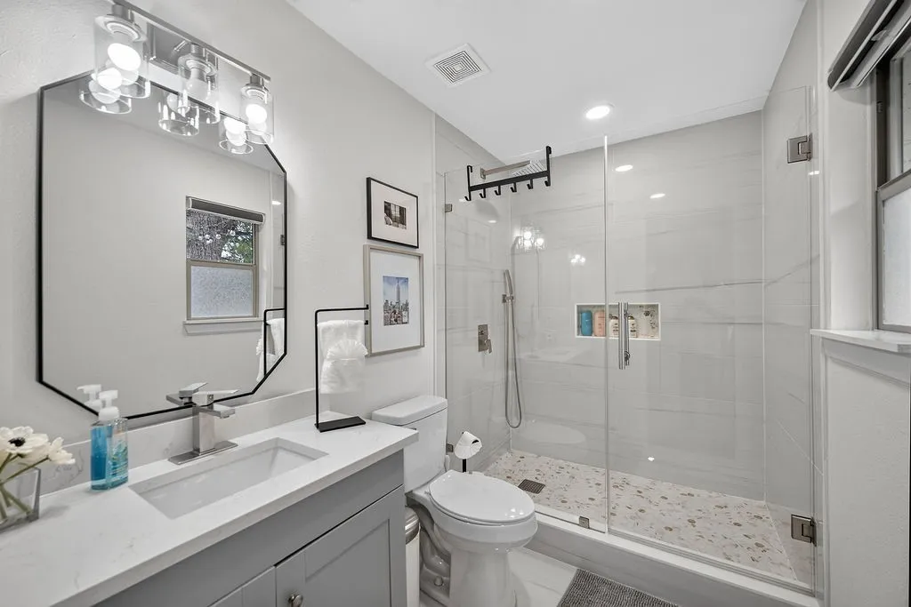 Modern vanity with a rectangular undermount sink, brushed nickel faucet, and a large geometric mirror