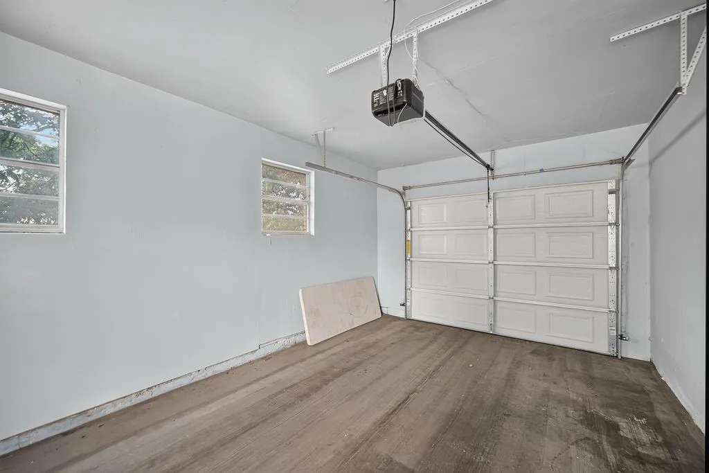 Single-bay garage featuring a panel-style door, an automatic opener, and two windows