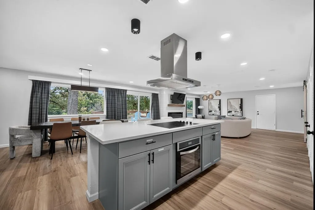 Open-concept living area featuring wood-finish flooring, recessed lighting, and large windows