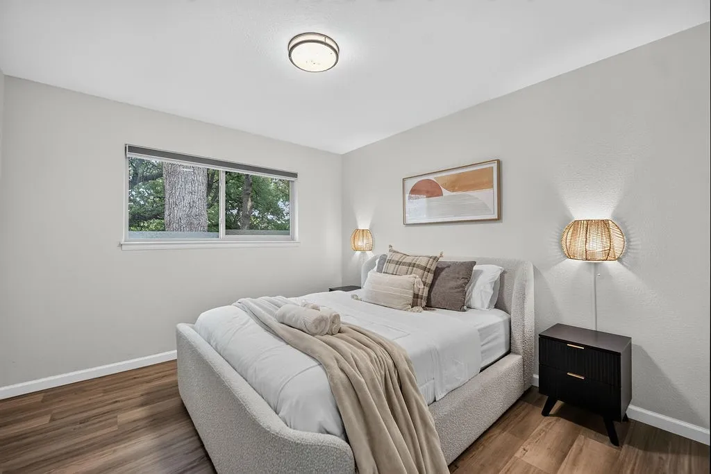 Recessed window with exterior foliage, wood-finish flooring, and a flush-mount ceiling light