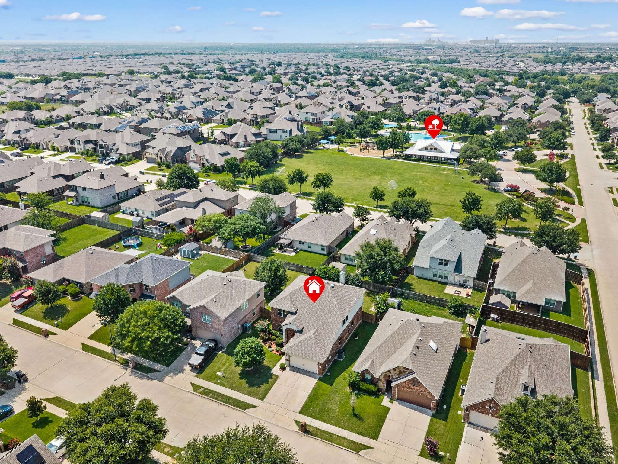 Expansive residential neighborhood featuring numerous single-family homes, manicured green spaces, and a community building with an outdoor pool