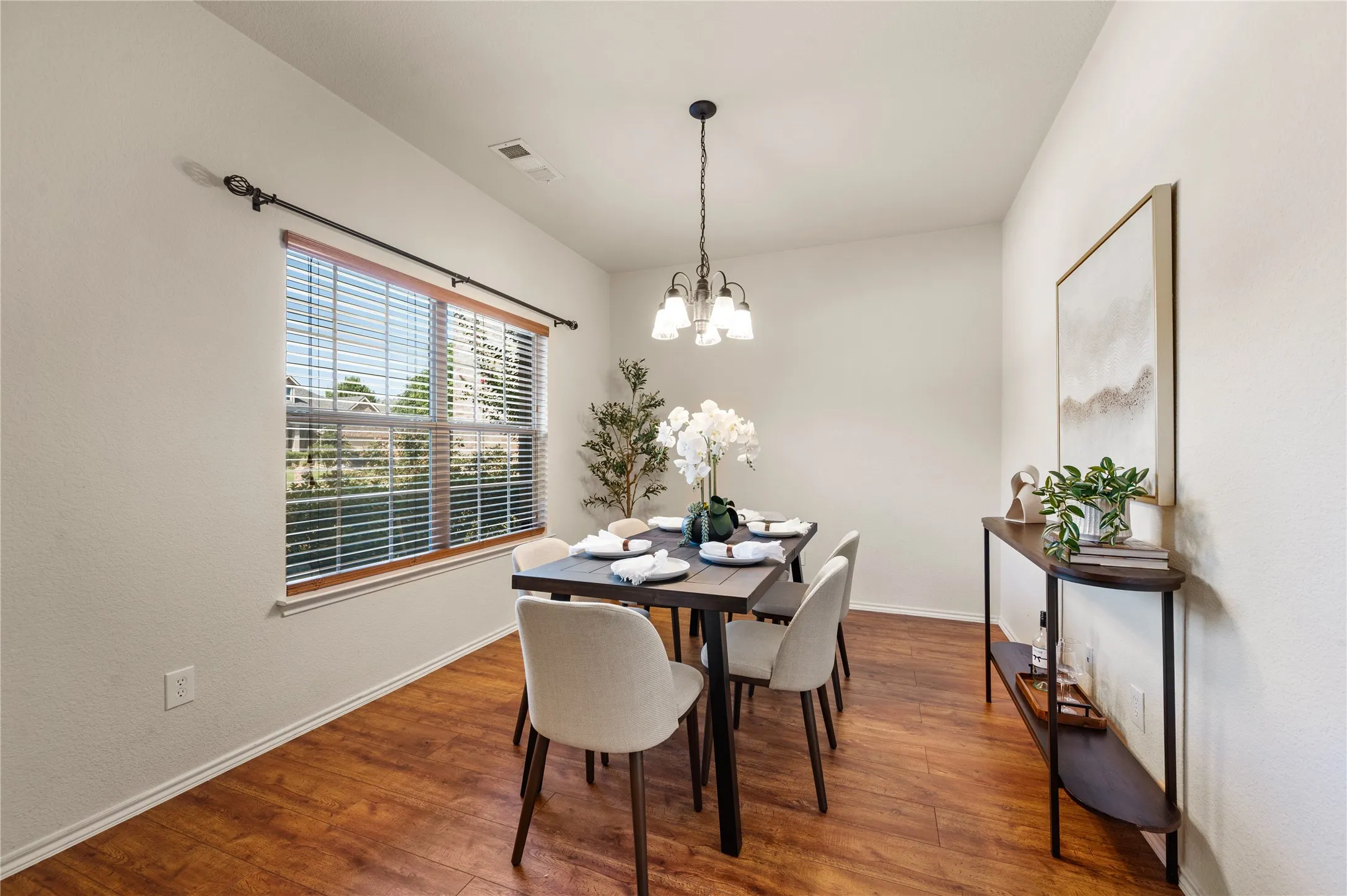 Recessed lighting and a multi-light chandelier illuminate wood-finish flooring