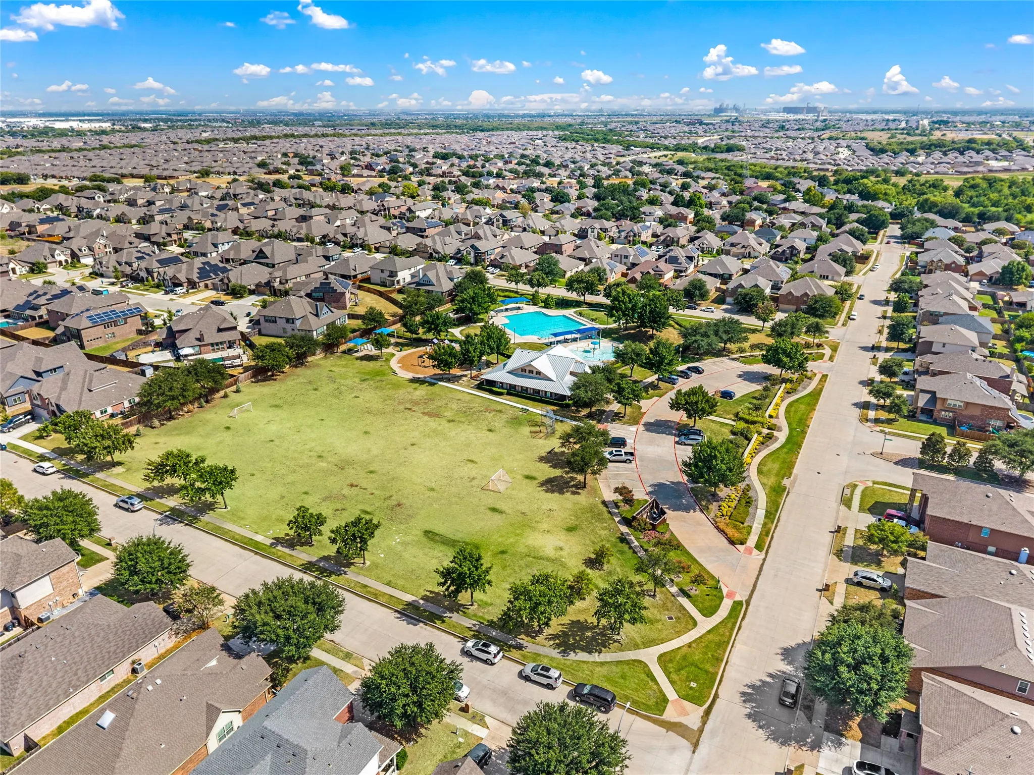 Expansive community green space, mature landscaping, community swimming pool, and dedicated parking areas
