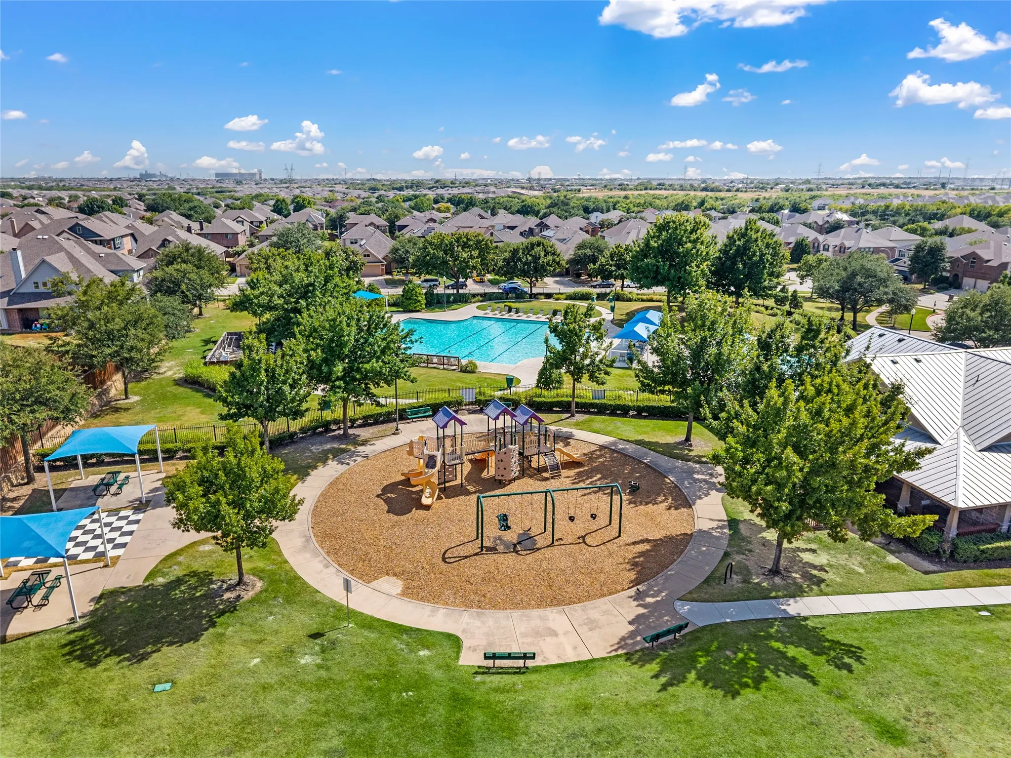 Community green space featuring a playground, swimming pool, and covered seating areas