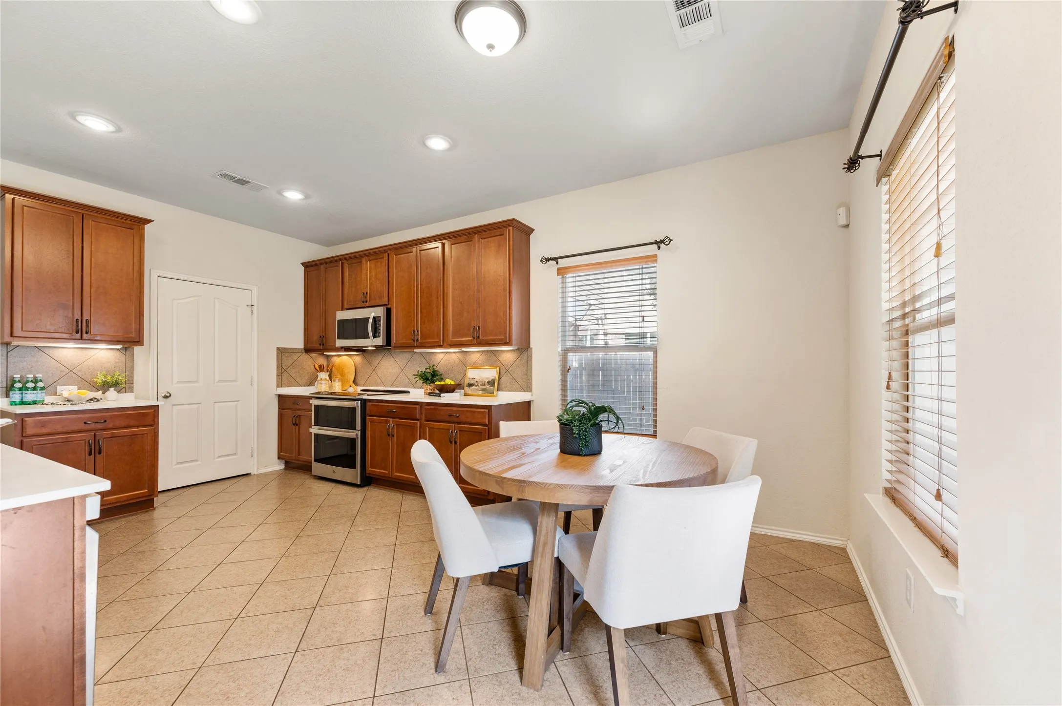Kitchen with wood cabinetry, stainless steel appliances, and tiled flooring