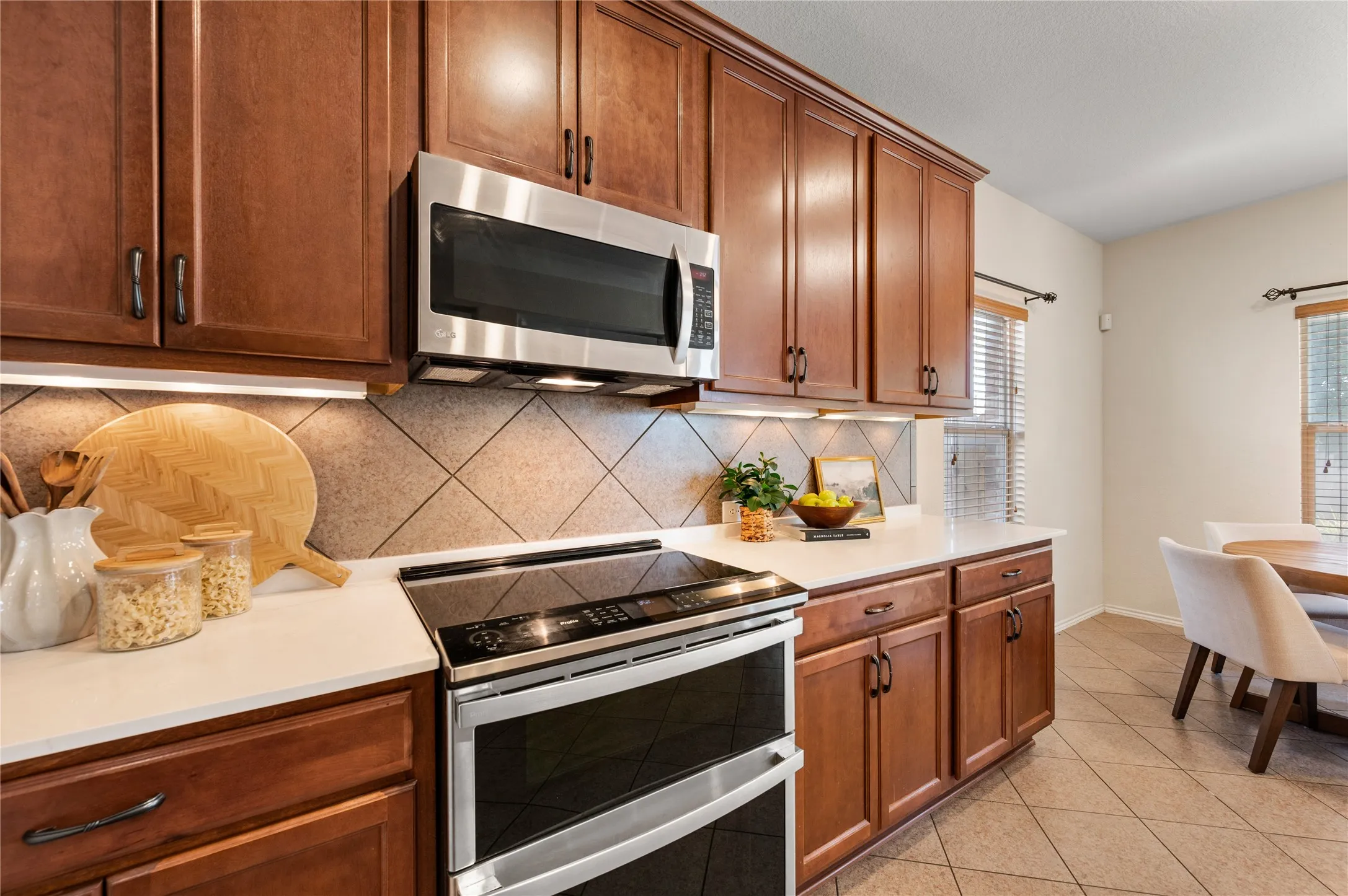 Wood-finish cabinetry paired with white countertops and a diagonal tile backsplash