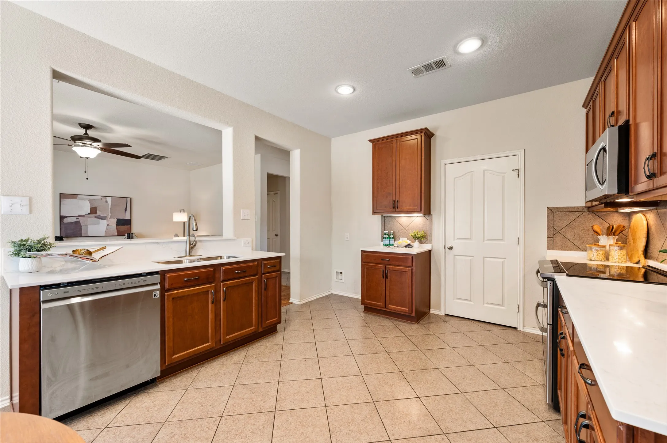 Kitchen featuring wood-finish cabinetry, stainless steel appliances, tile flooring, and recessed lighting
