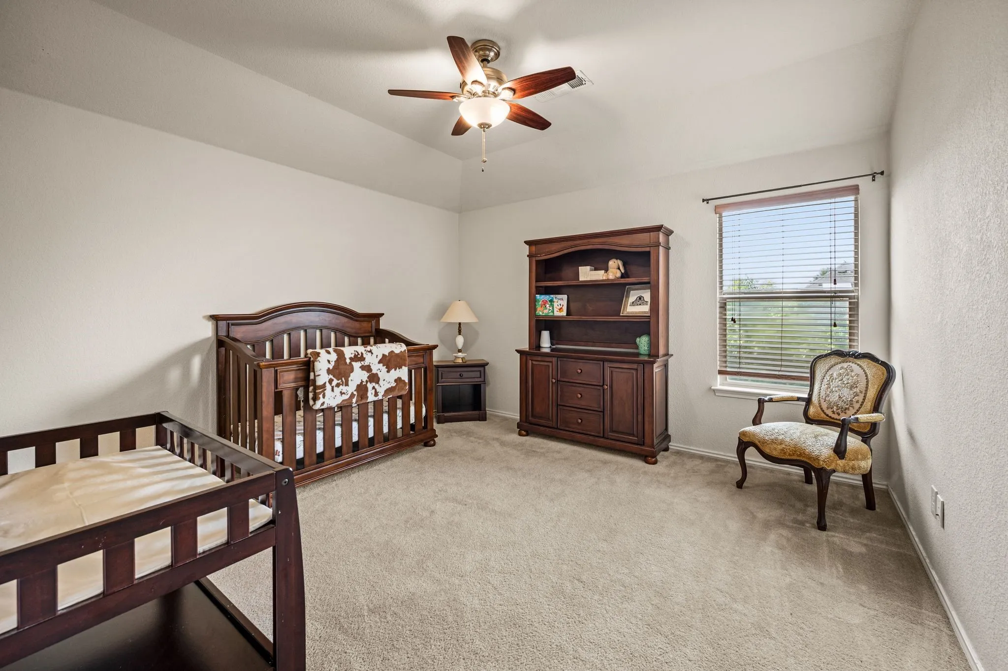 Carpeted room with a ceiling fan light fixture and a window with blinds