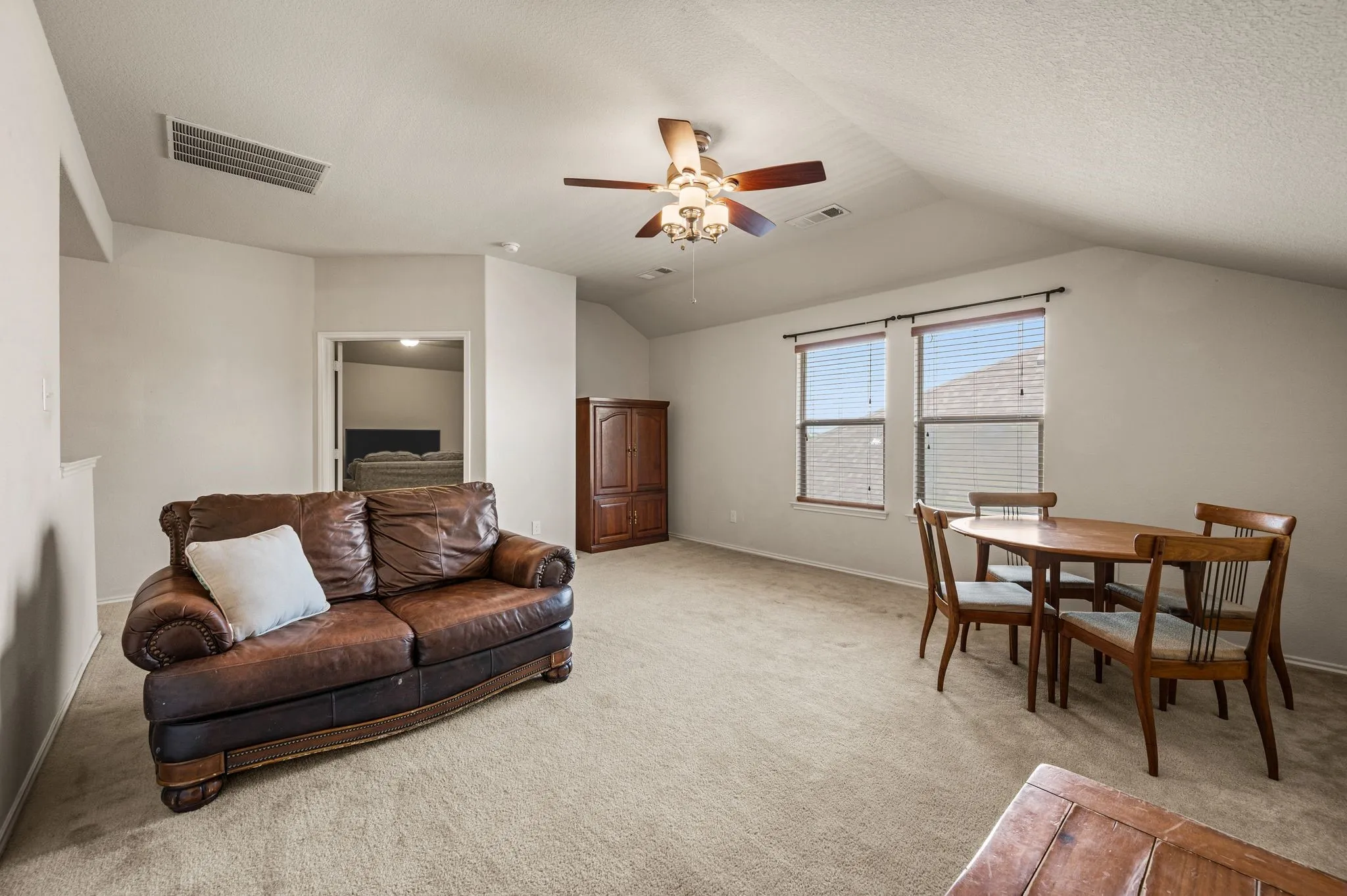 Carpeted room featuring vaulted ceilings, a ceiling fan, and multiple windows