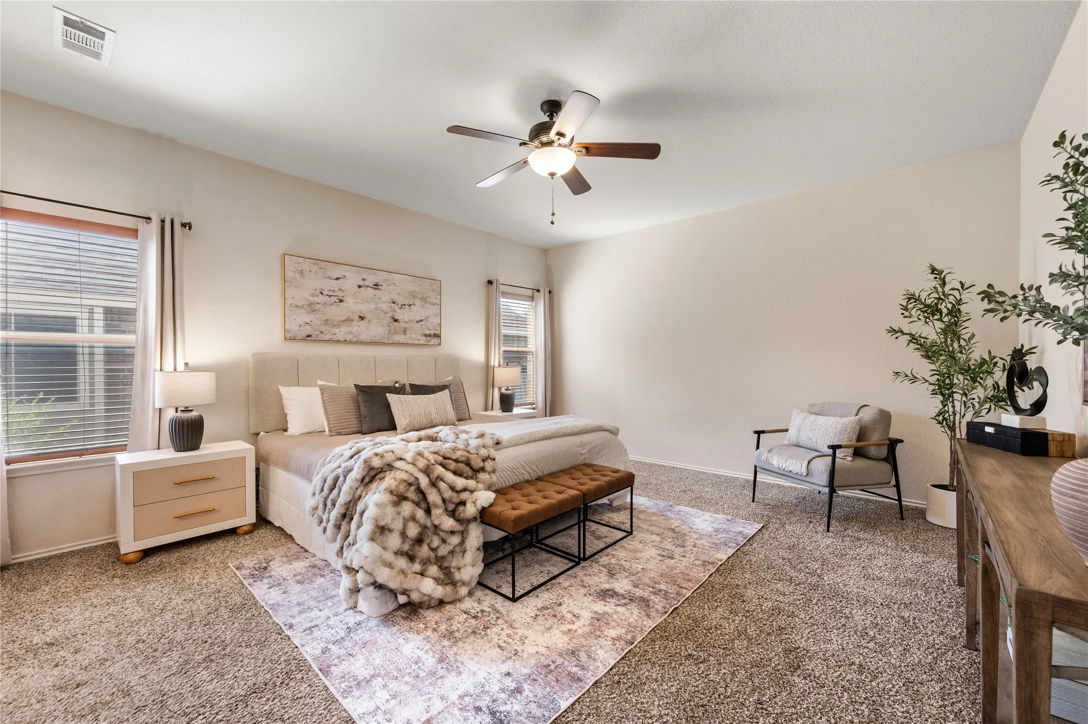 Carpeted room featuring a ceiling fan with integrated lighting, multiple windows with blinds, and neutral-toned walls