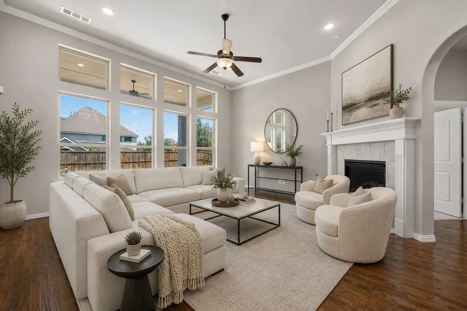 virtually staged. Spacious living area featuring high ceilings, a bank of transom windows, wood-finish flooring, a ceiling fan, and a fireplace with a mantel