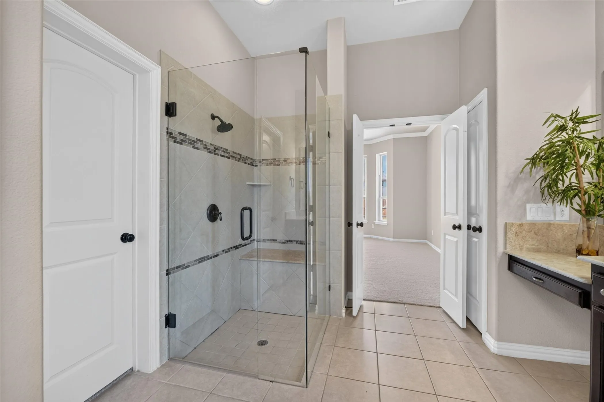 Walk-in shower with clear glass enclosure, tile walls, and built-in bench