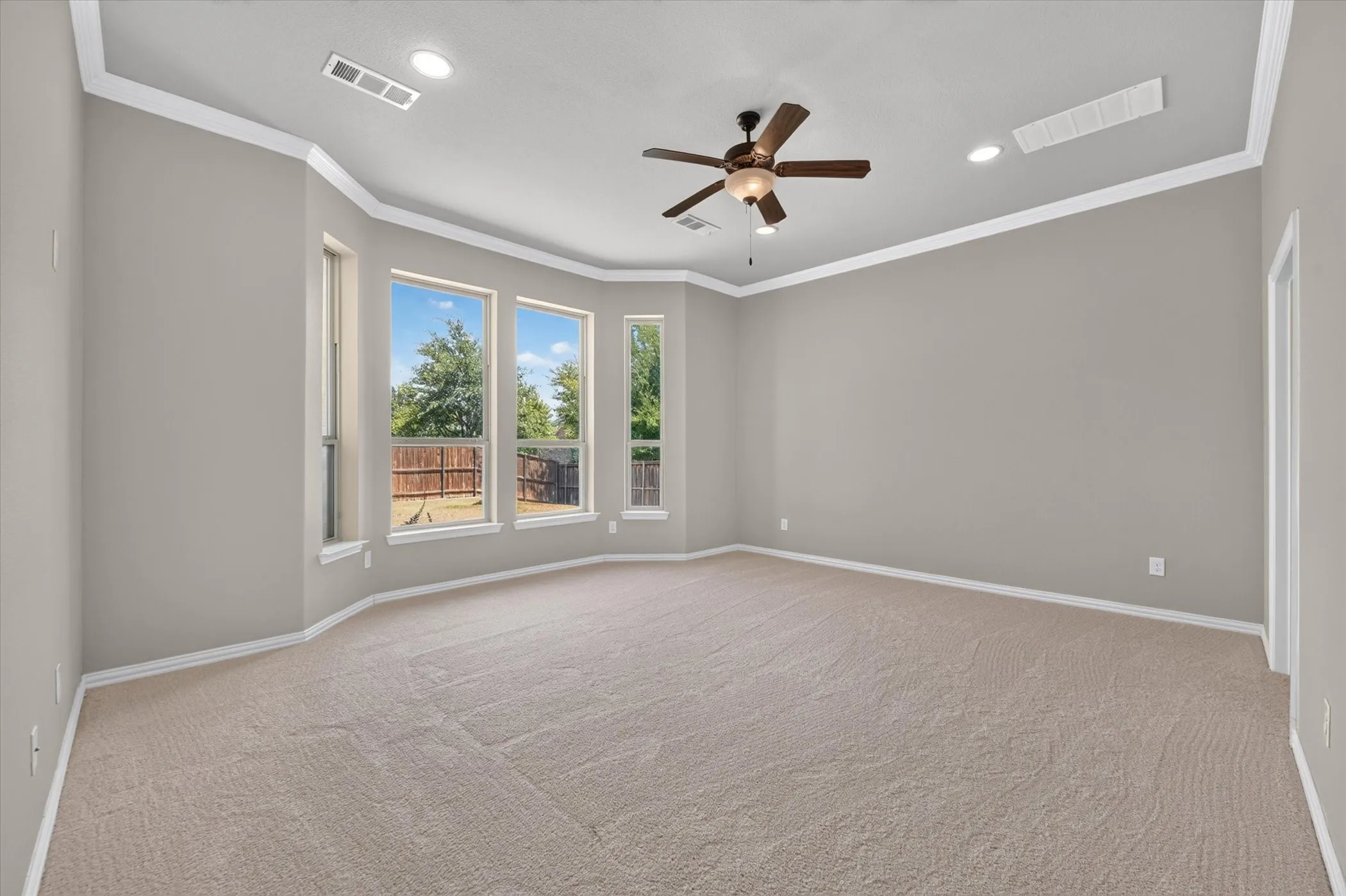 Spacious room featuring a bay window, recessed lighting, ceiling fan, and neutral carpeting