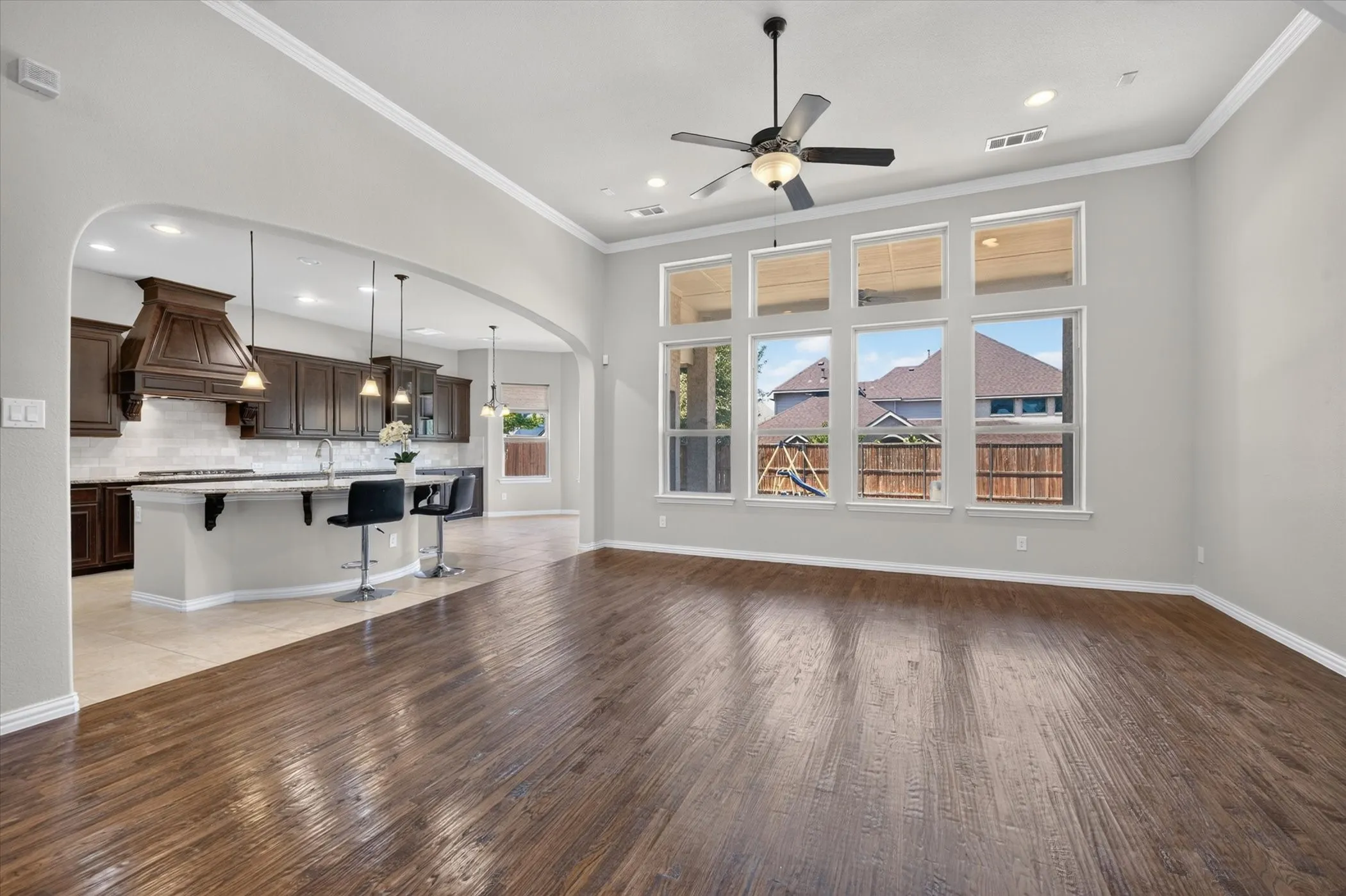Wood-finish flooring, high ceilings with recessed lighting, and a ceiling fan
