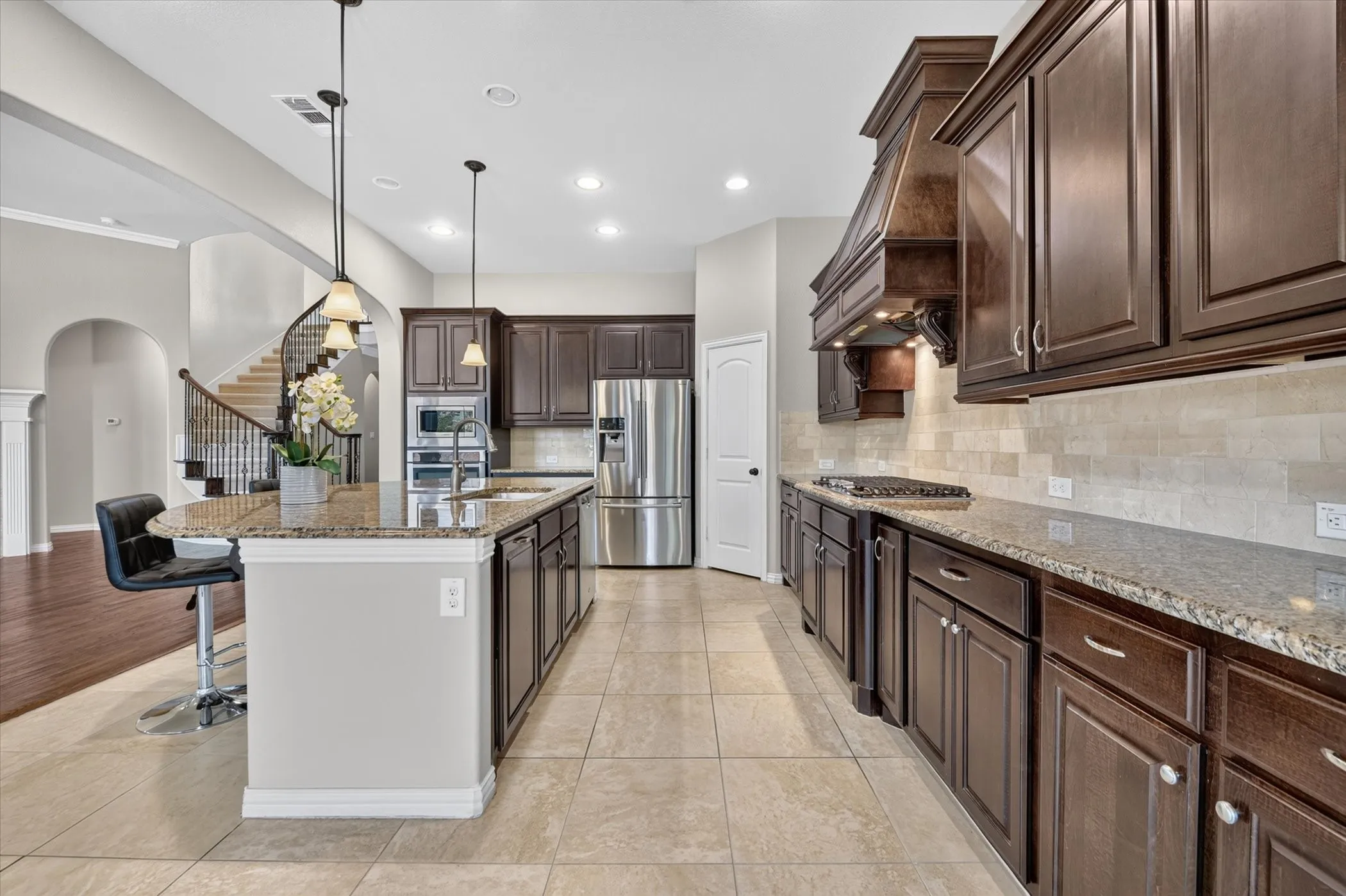 Kitchen featuring dark wood-finish cabinetry, granite countertops, stainless steel appliances, and a tile backsplash